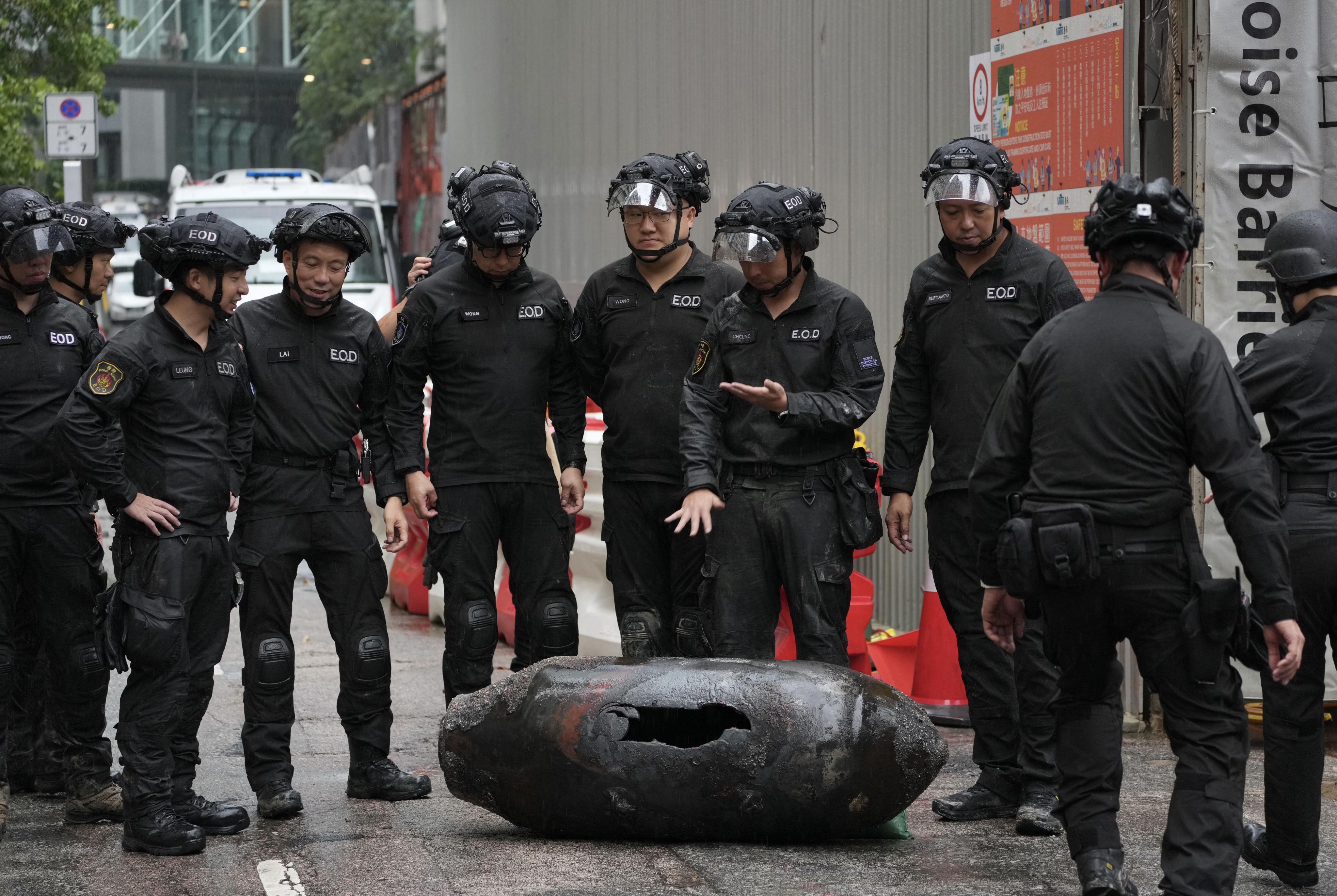 Officers from the explosive ordnance disposal bureau stand beside the shell casing on Pan Hoi street in Quarry Bay. Photo: Karma Lo