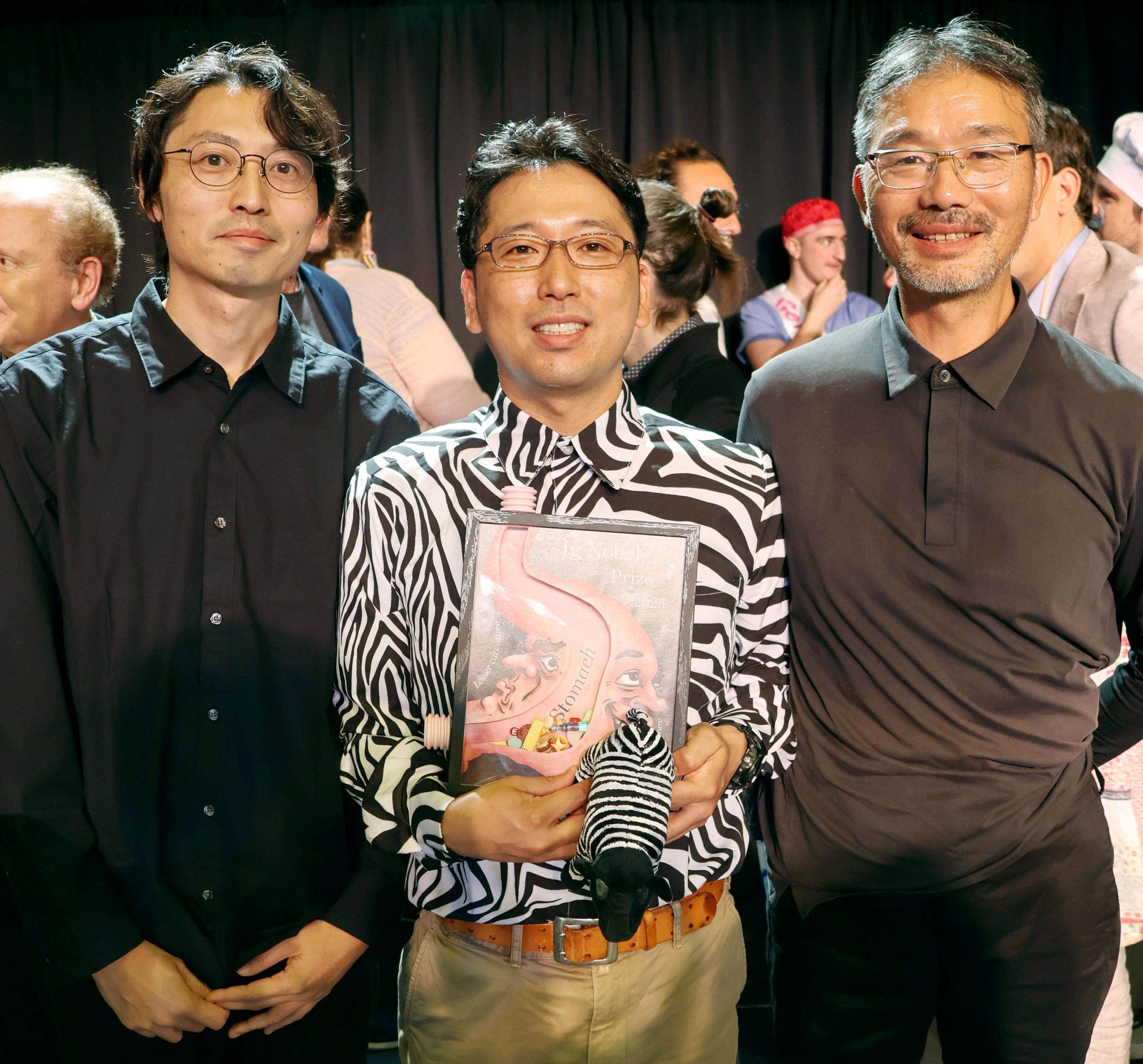 (From left) Kazato Oishi, Tomoki Kojima and Sei Sato, pose for photos in Boston on Thursday after their team won the Ig Nobel Prize in Biology. Their experiment showing that painting zebra-like stripes on cattle significantly reduces the number of biting flies landing on them was recognised at the ceremony in Boston. Photo: Kyodo