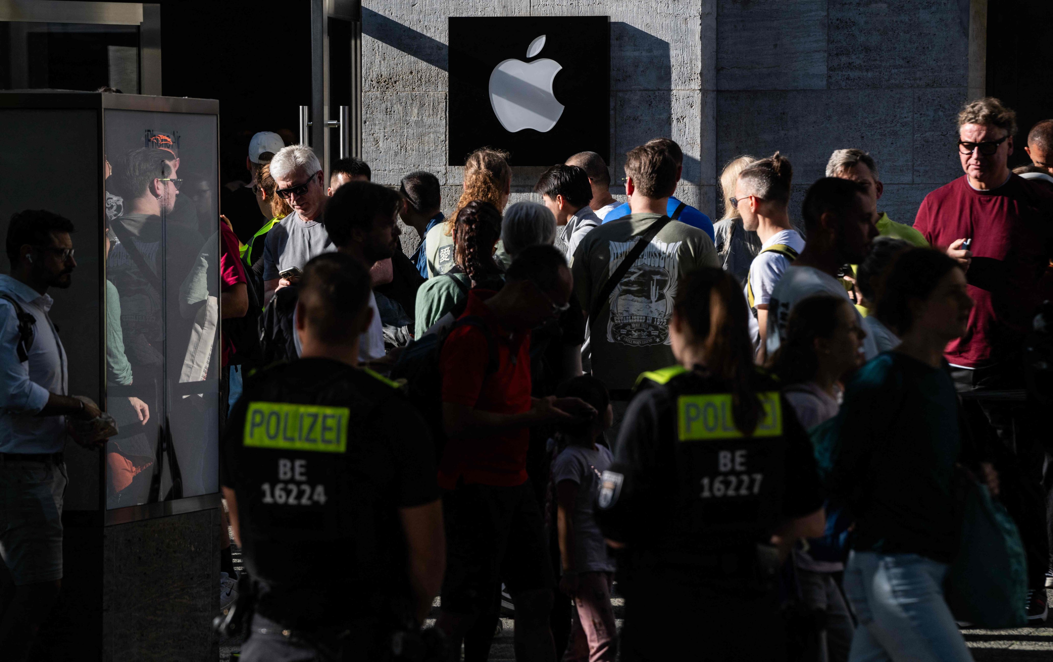 Police officers watch over customers queuing up in front of an Apple store in Berlin on Friday. Photo: AFP