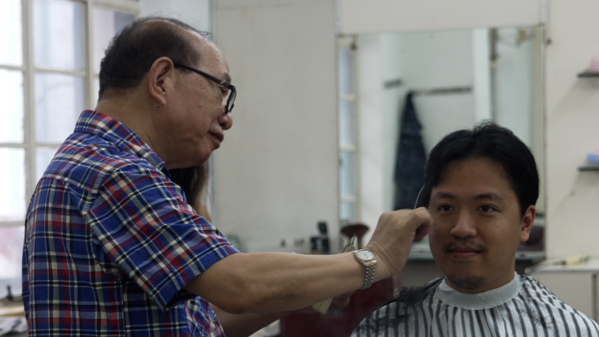 78-year-old barber Luk Chung-yan doing a haircut