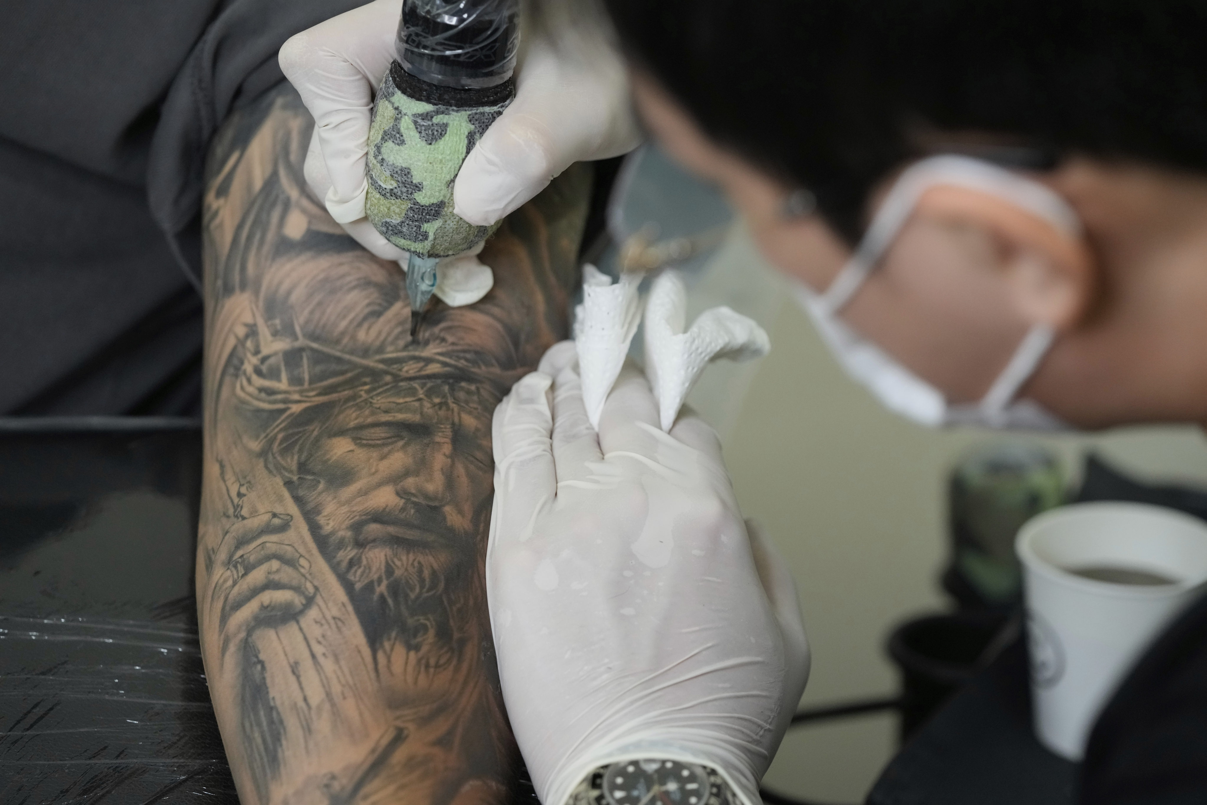 Tattoo artist Song Jaemin works to tattoo an image of Jesus Christ on the forearm of Lee Byong-joo at his studio in Goyang, South Korea. Photo: AP