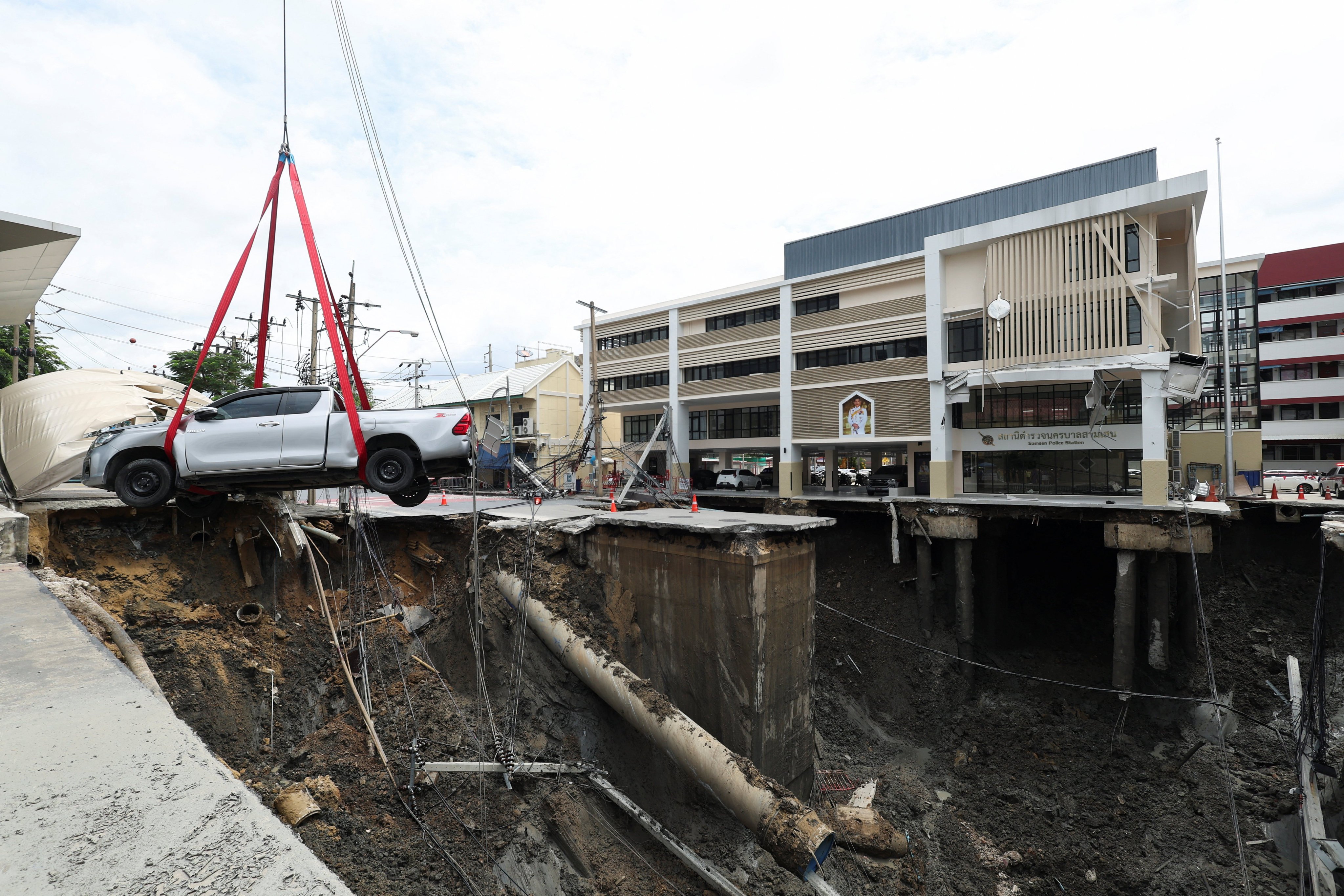 A vehicle teetering on the edge of a massive sinkhole that opened on Samsen Road in Bangkok is moved to a safe space on Wedmesday. Photo: Reuters