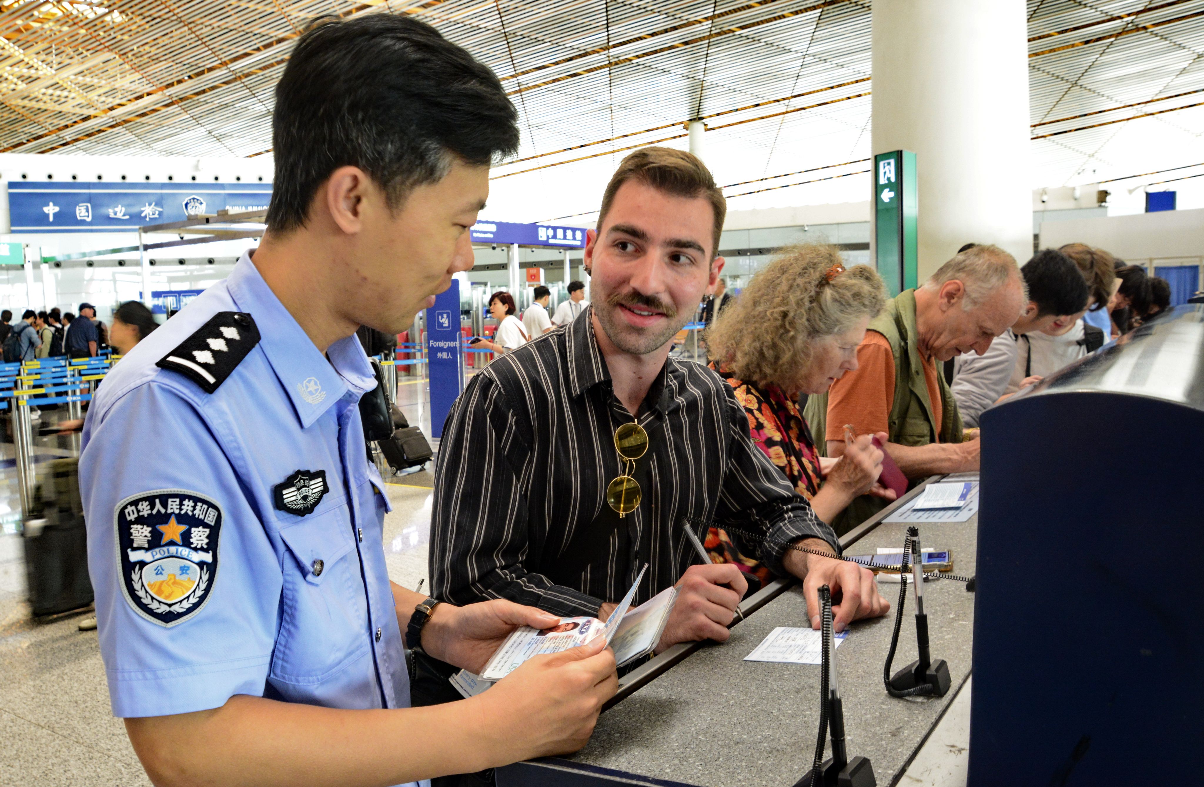 A police officer helps an American tourist fill out an entry registration card at an airport in Beijing. China’s visa-free entry policies have sparked a surge in overseas tourism over the past two years. Photo: Xinhua