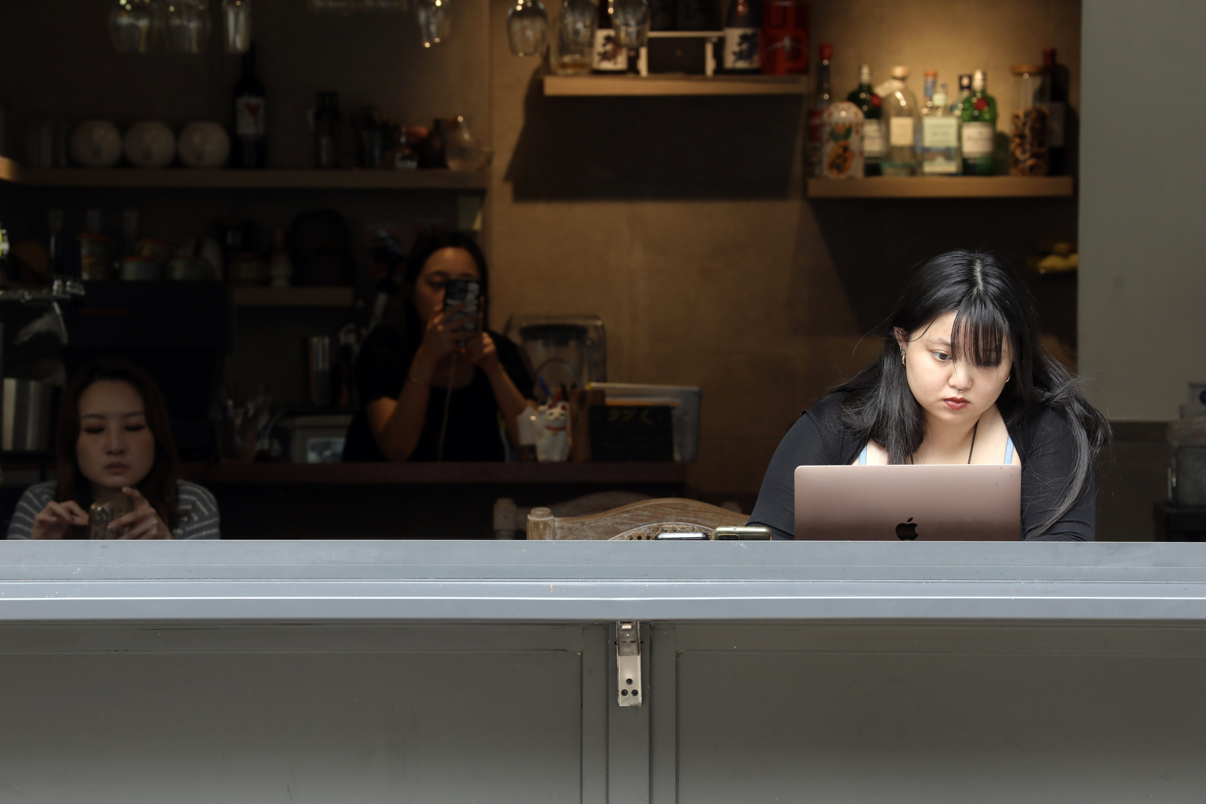 Young women using their laptops and phones in a Hong Kong cafe.  Online platforms have been buzzing with discussions about the work culture of Gen Z people. Photo: Sun Yeung