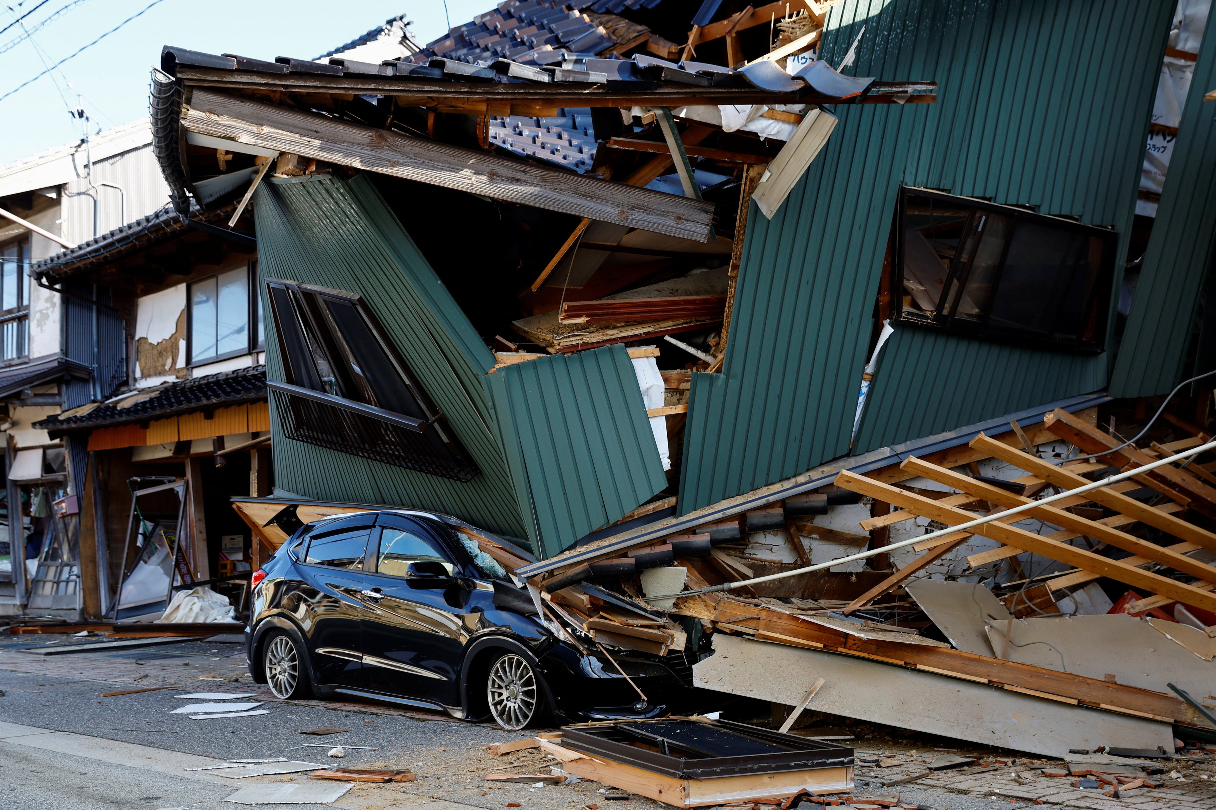 A damaged car stands near a collapsed house, following an earthquake, in Nanao, Japan, on January 2, last year. Photo: Reuters