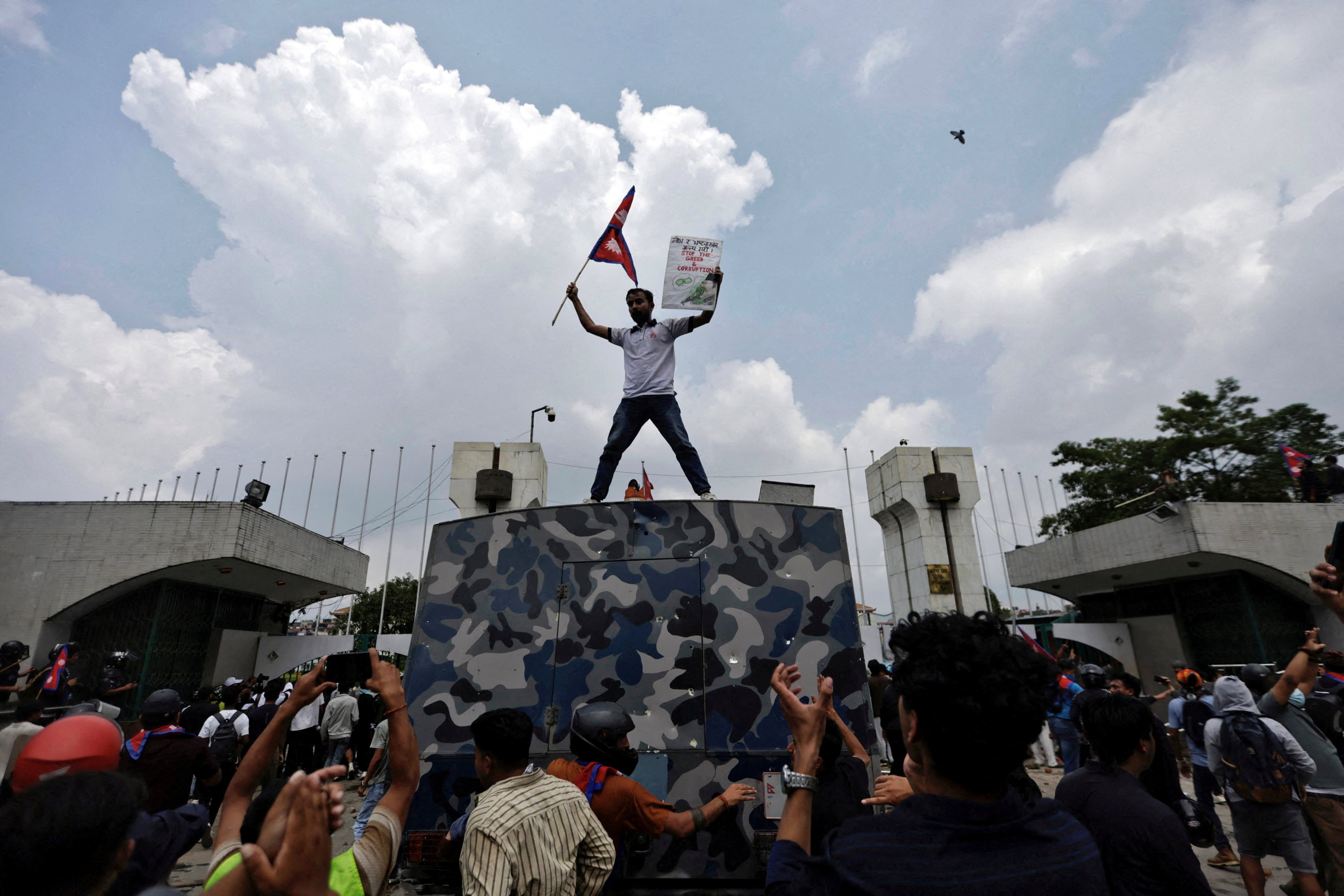 A young protester waves the Nepalese flag as he stands atop a vehicle near the entrance of parliament in Kathmandu on September 8. Photo: Reuters
