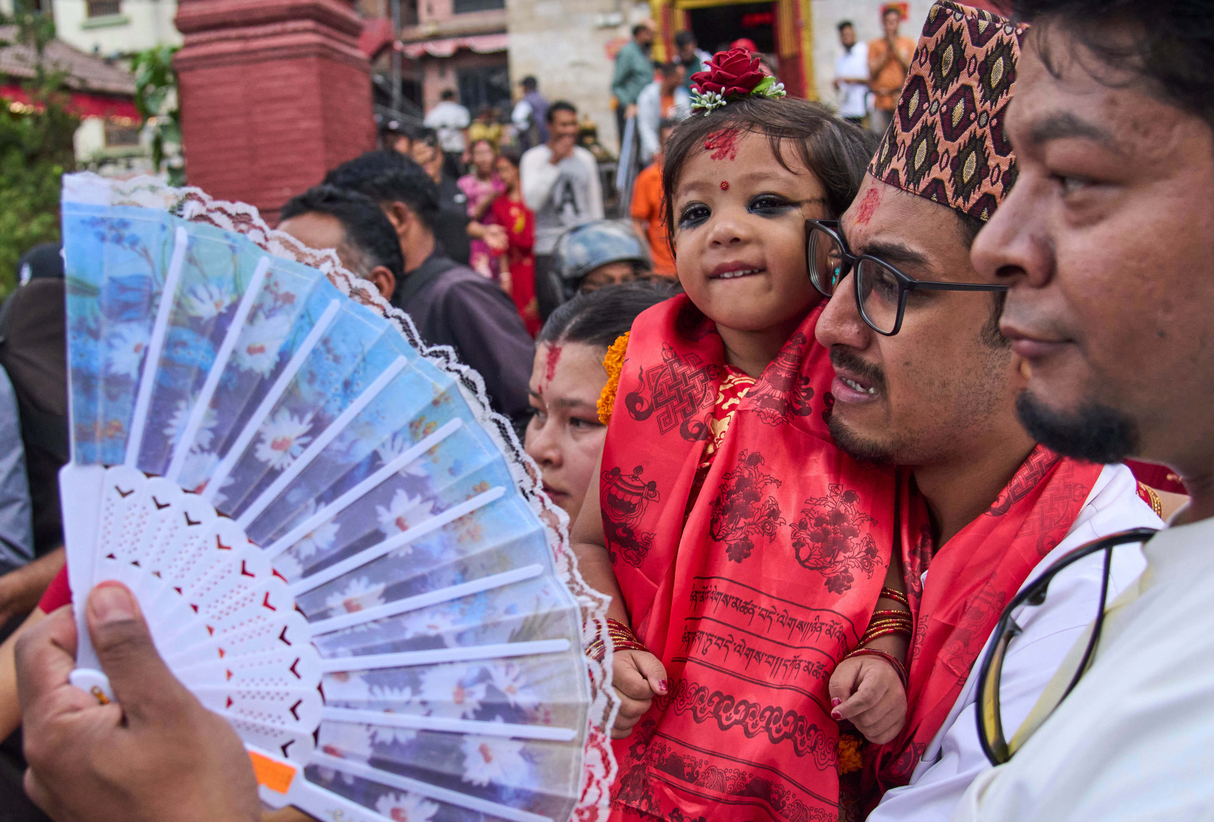 Nepal’s newly appointed living goddess, Kumari Aryatara Shakya, is carried by her father as they walk towards Kumari Ghar, the temple palace where she will be living in Kathmandu, Nepal on Tuesday. Photo: AP