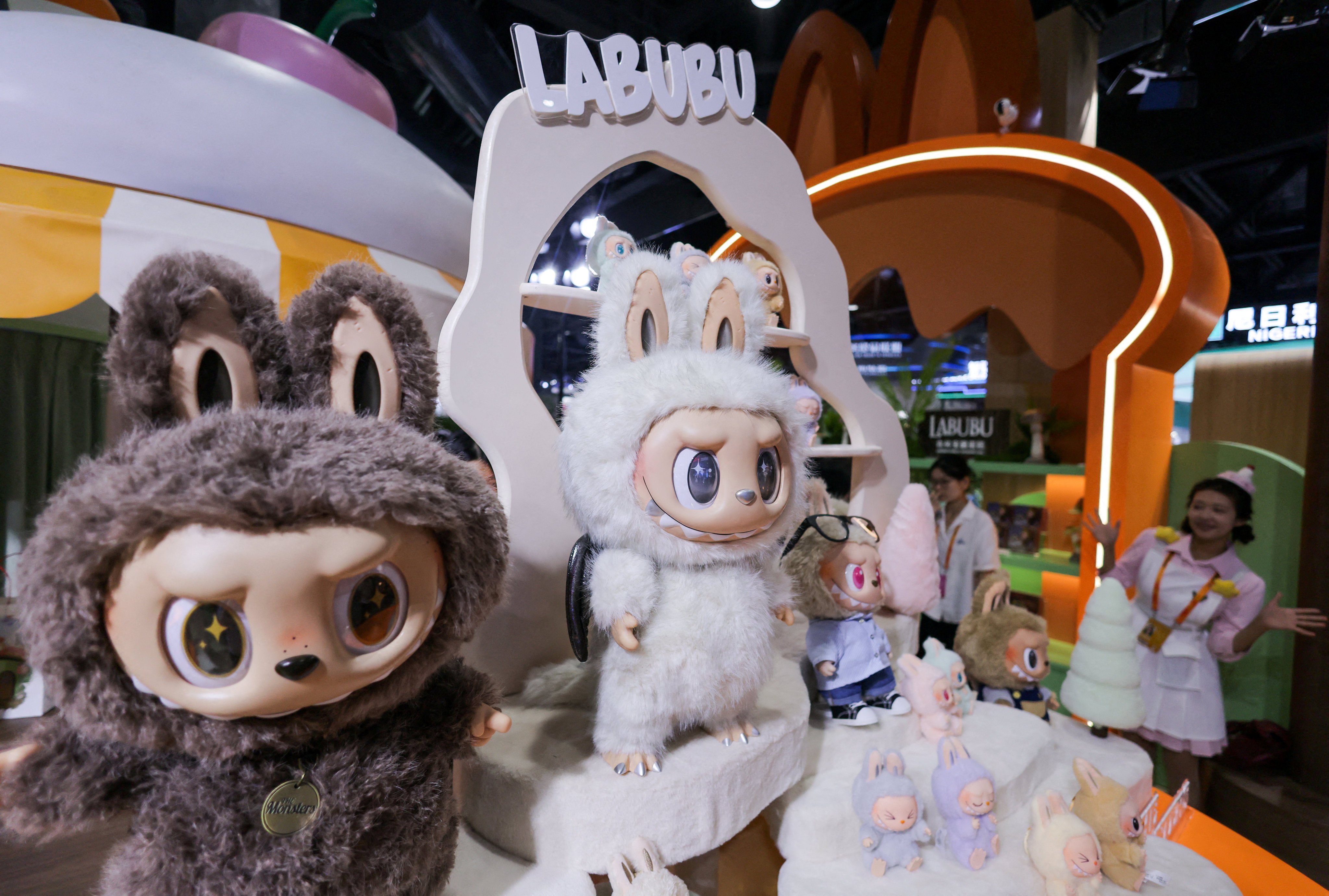 An employee stands next to Labubu toys at Pop Mart’s booth at the China International Fair for Trade in Services in Beijing, in September 2025. Pop Mart is planning to invest in “developing content, theme parks, store displays” for Labubu. Photo: Reuters