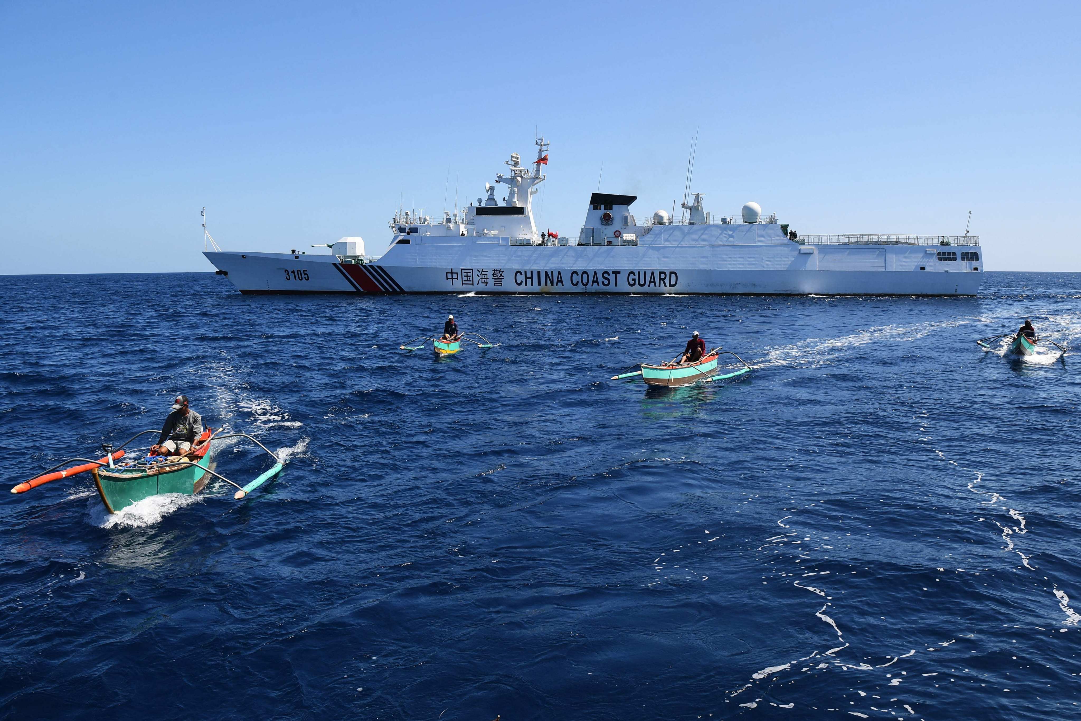 A Chinese coastguard ship patrols near Philippine fishing boats near Scarborough Shoal. Photo: AFP