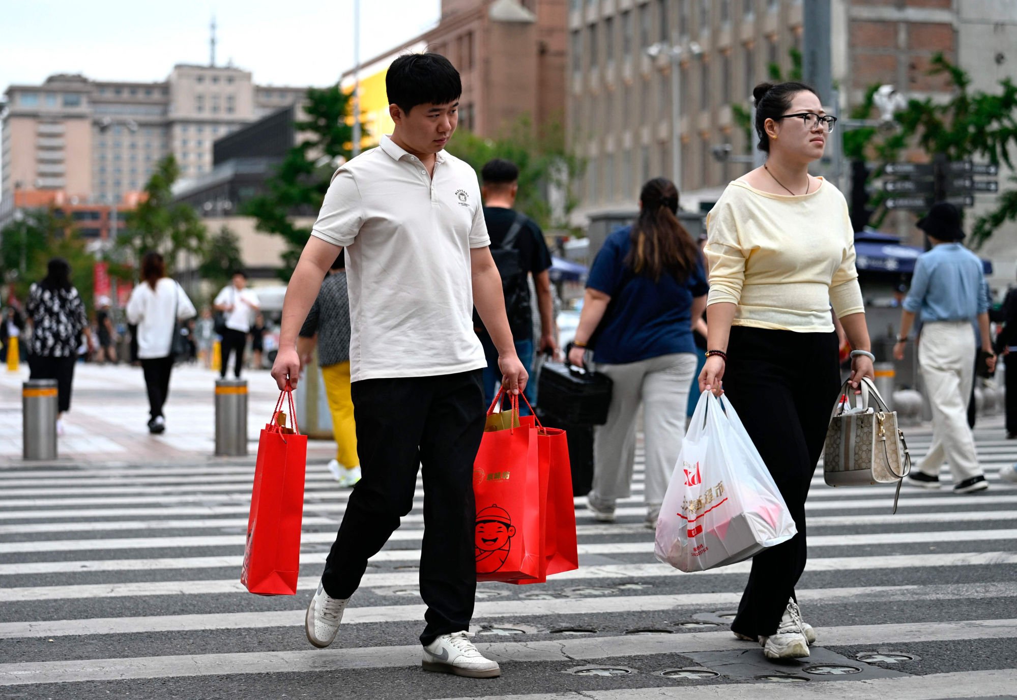 People carry shopping bags while crossing a street in Beijing on September 15, 2025. Photo: AFP People carry shopping bags while crossing a street in Beijing on September 15, 2025. Photo: AFP