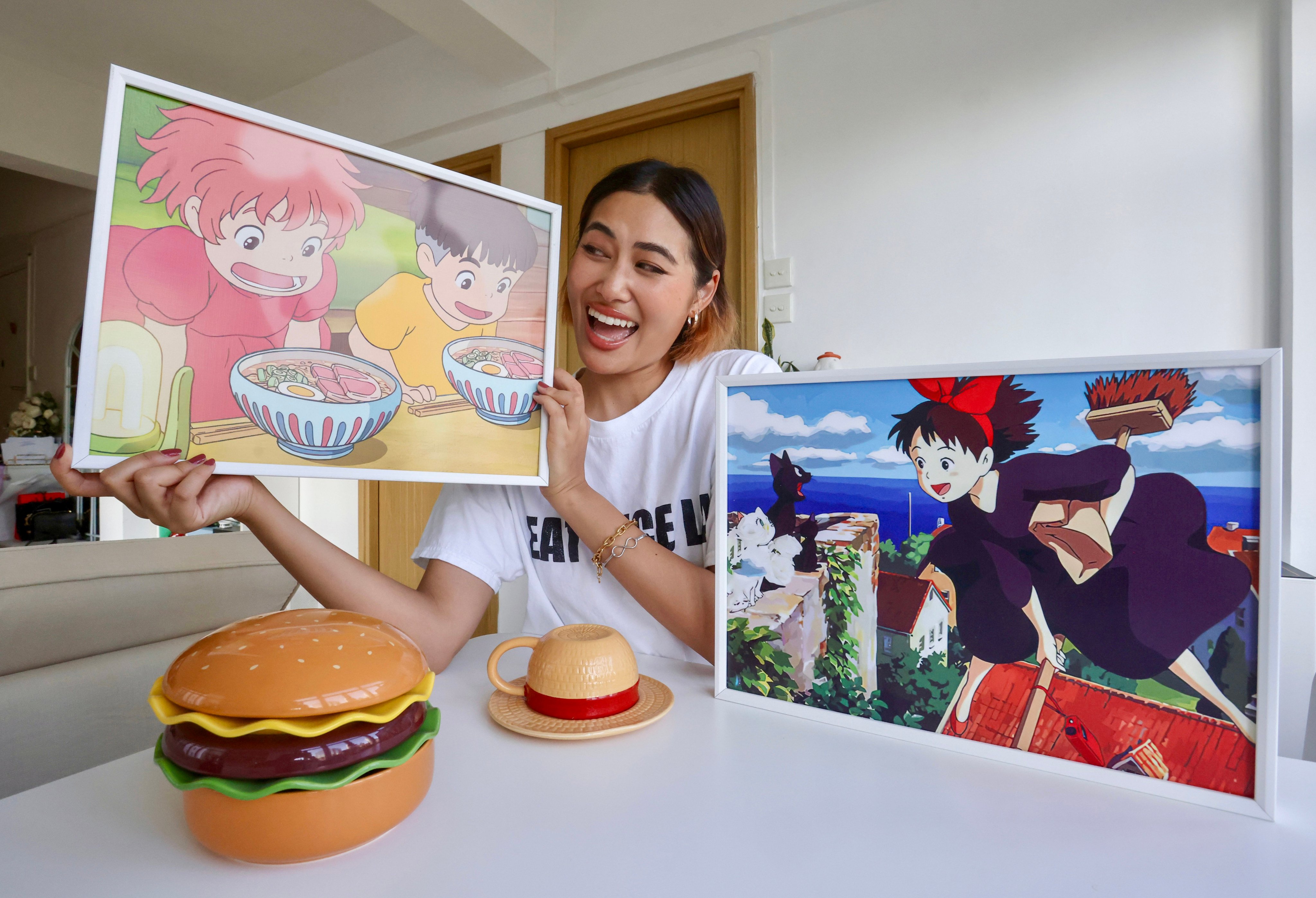 Lukian Wang holds a picture of a scene from Studio Ghibli’s 2008 anime Ponyo at her home in Tsim Sha Tsui, Hong Kong. Her first viral video was of her making instant noodles inspired by food in the film. Photo: Jonathan Wong