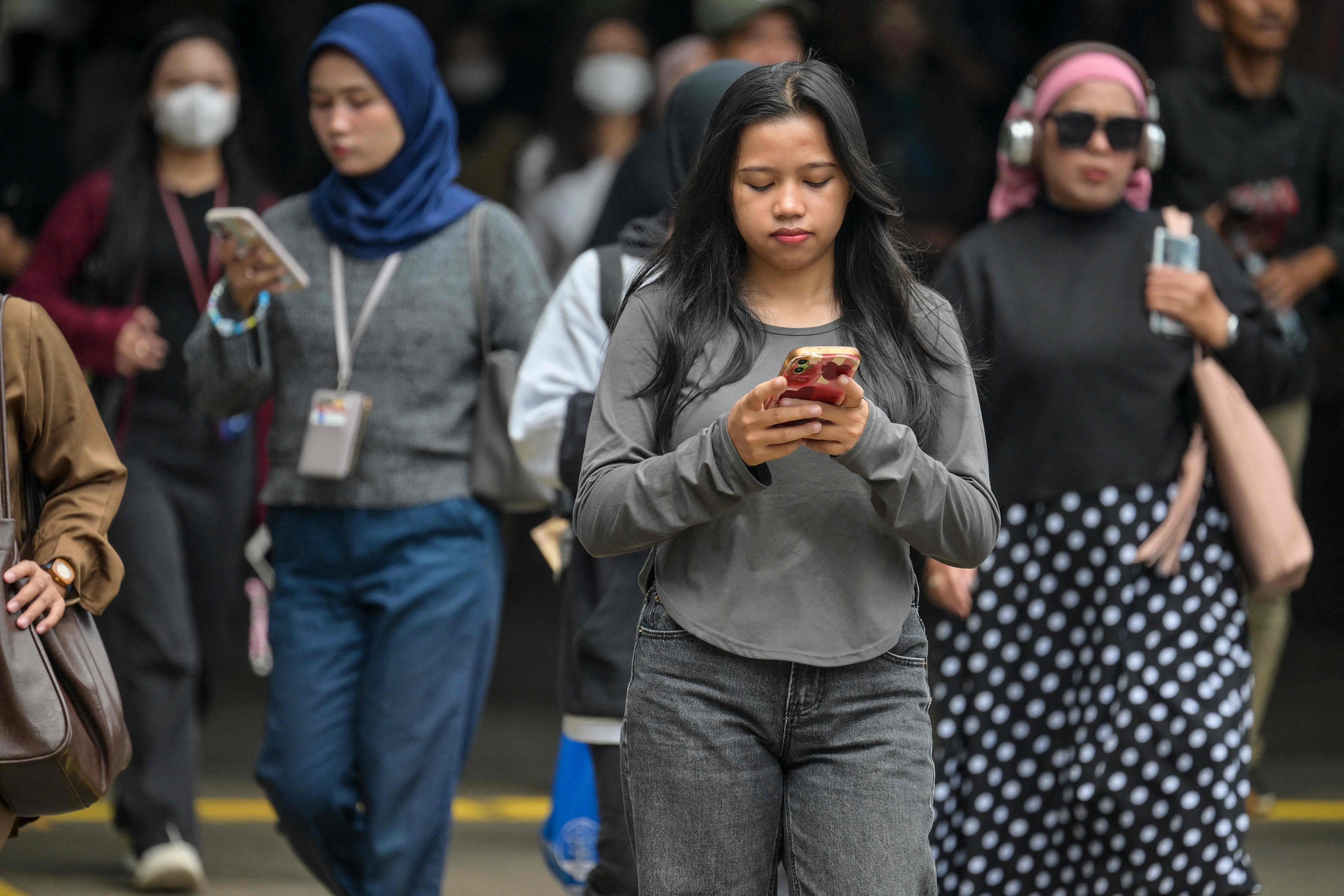 People use their phones while walking on a street in Jakarta, Indonesia, on September 19. Photo: AFP