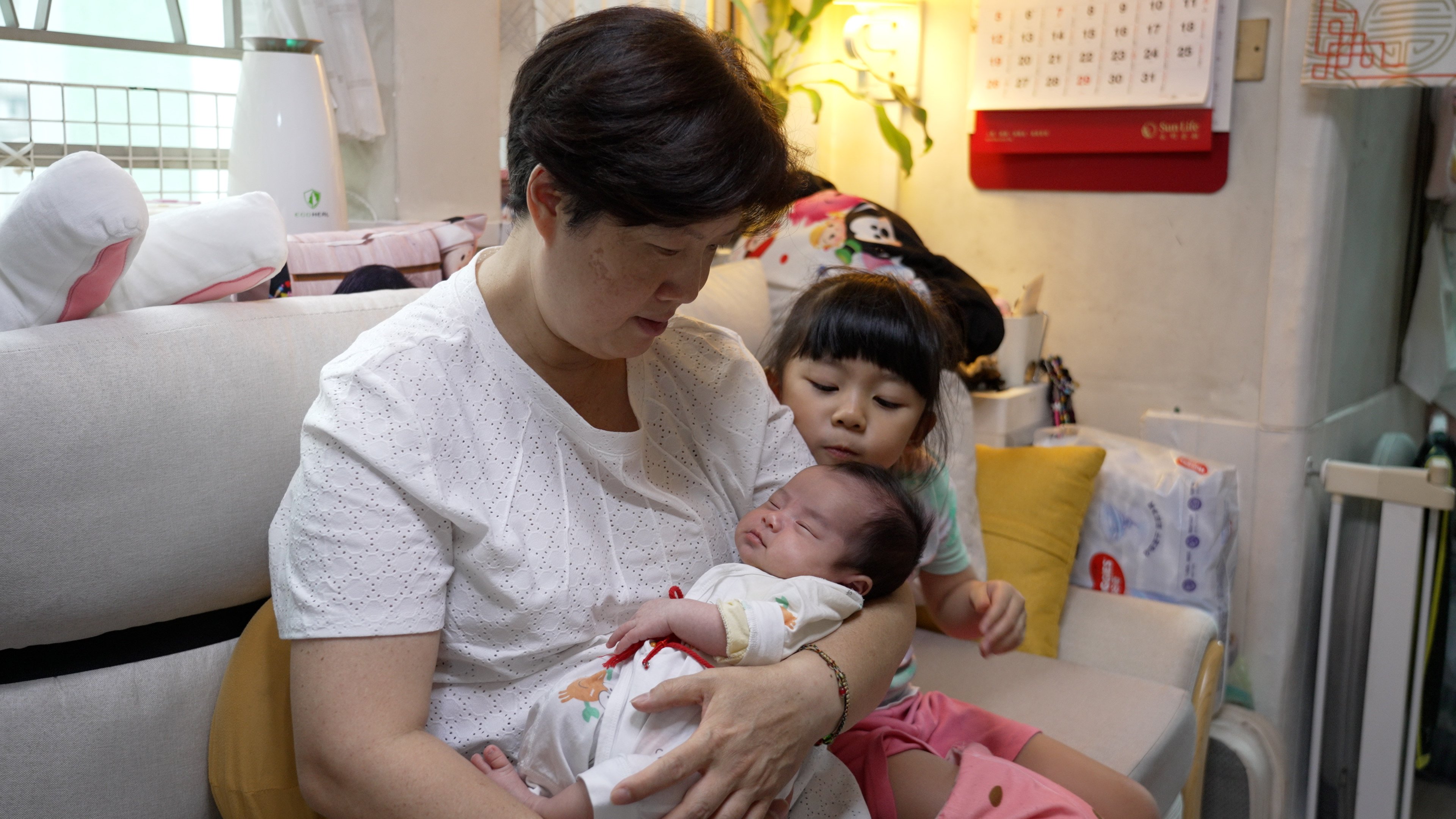 Lilian Chan, 58, holding her second daughter Gia Wong. Her first daughter Miracle Wong sits next to her.