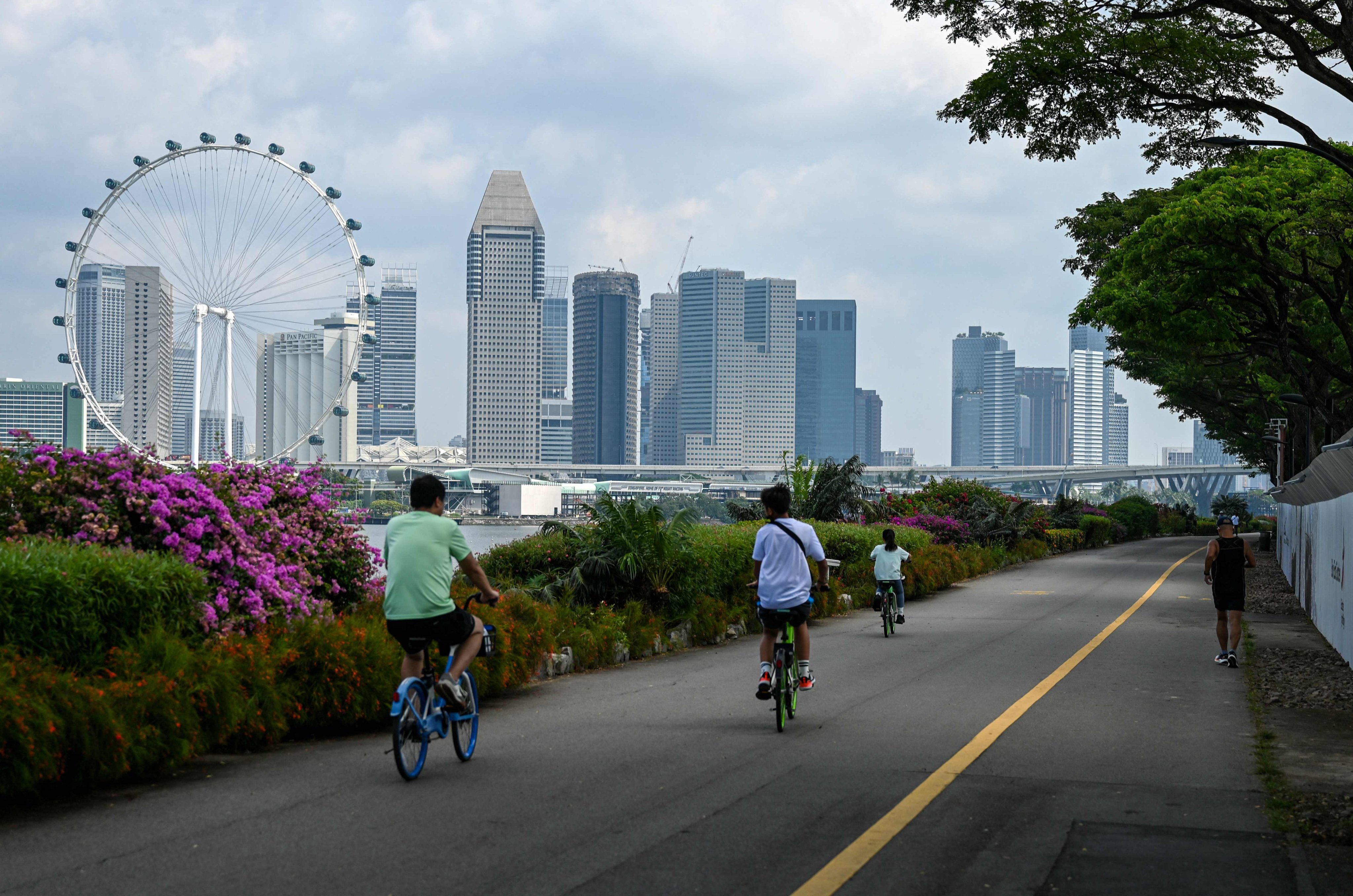 People cycle along a track backdropped with the city skyline in Singapore in June. The city state crossed the 6 million population threshold in 2024. Photo: AFP