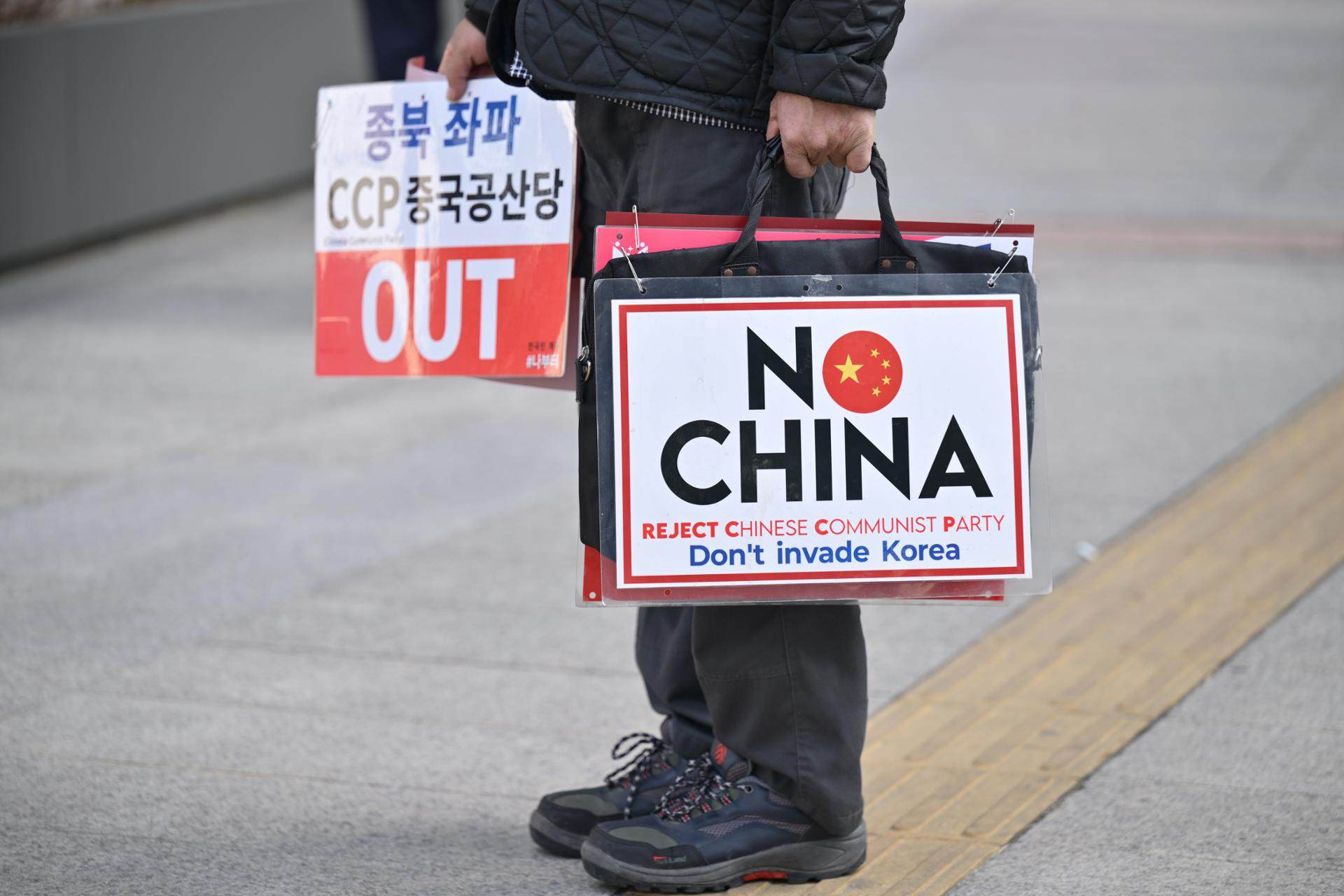 A conservative protester carries signs with anti-China slogans during a rally near the Chinese Embassy in Myeong-dong, Seoul, on August 13. Photo: The Korea Times