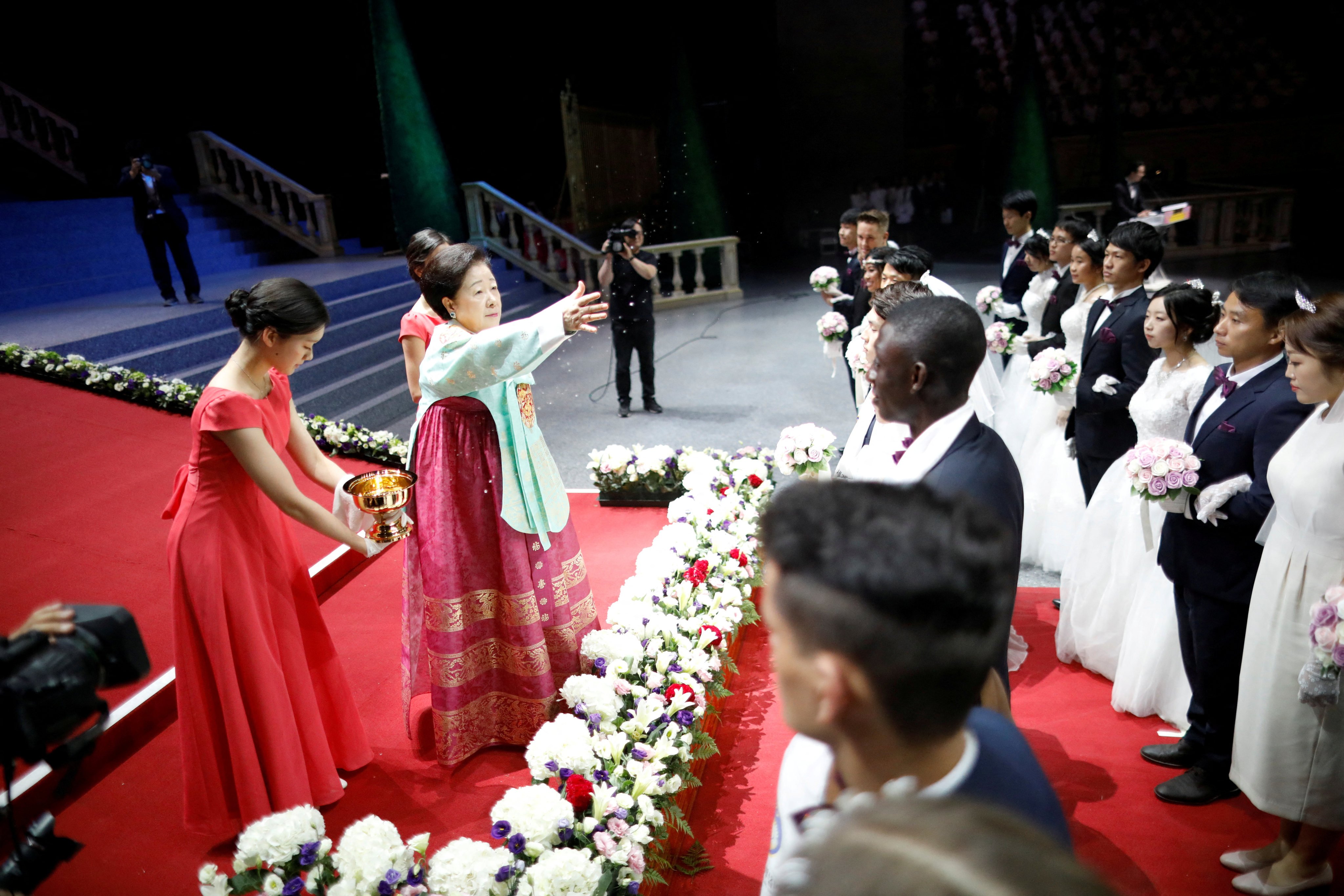 Han Hak-ja, widow of  Moon Sun-myung, sprays holy water to bless couples during a Unification Church mass wedding ceremony. Photo: Reuters