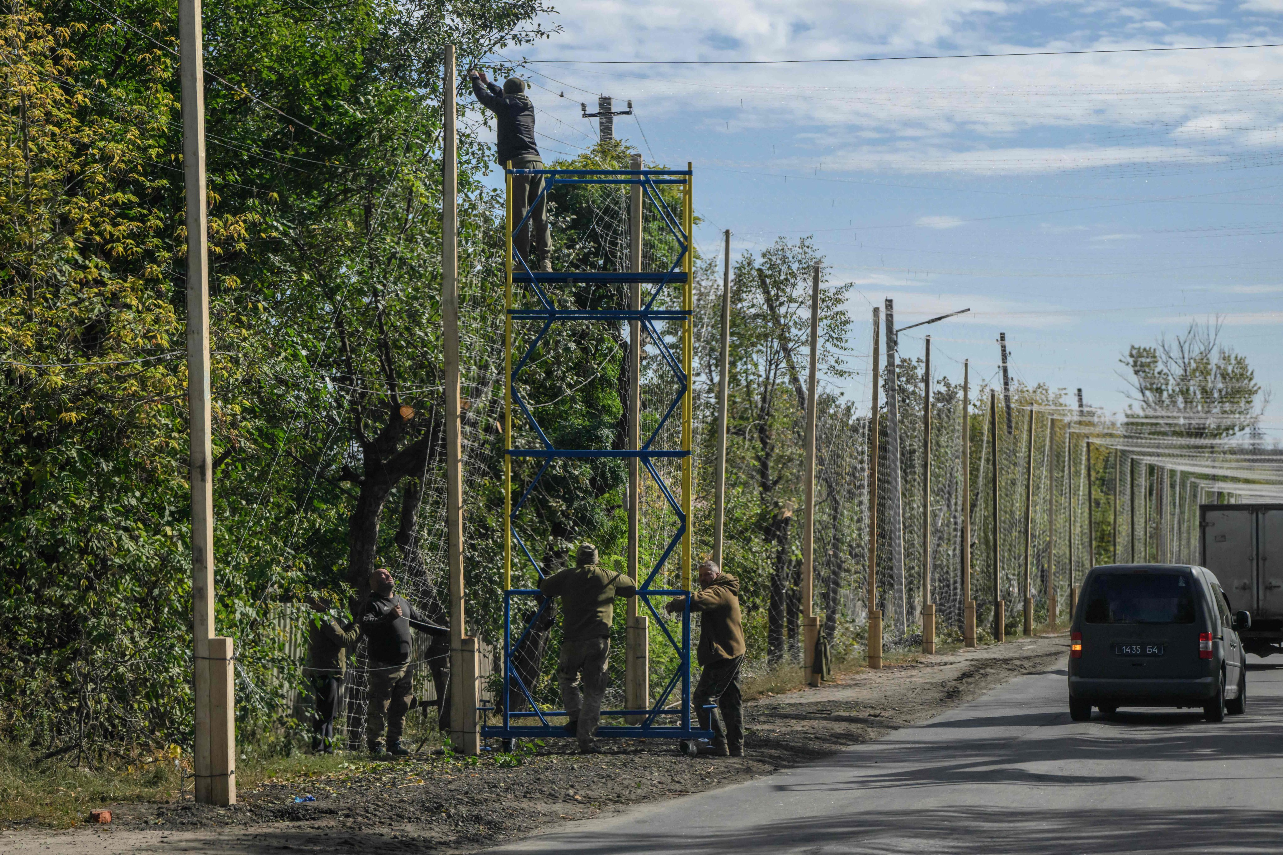 Workers install anti-drone nets along a road near Oleksandriya, Ukraine, on Thursday. Photo: AFP