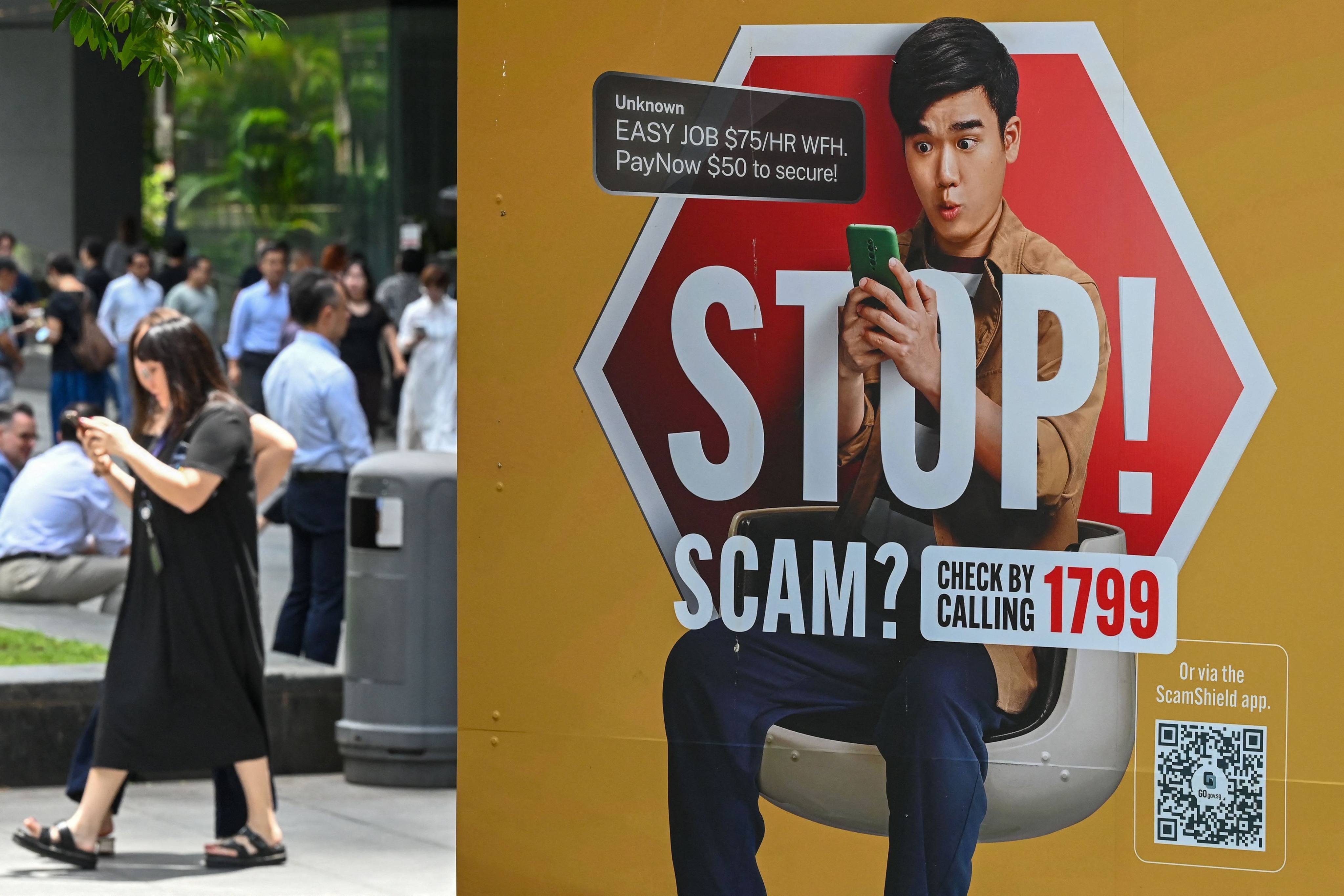 People walk past a poster warning of scam threats, in the business district of Raffles Place in Singapore, on September 3. Hong Kong’s police chief met top security officials from Cambodia, Vietnam, Singapore and South Korea recently to discuss closer collaboration in combating scams and enhancing training. Photo: AFP