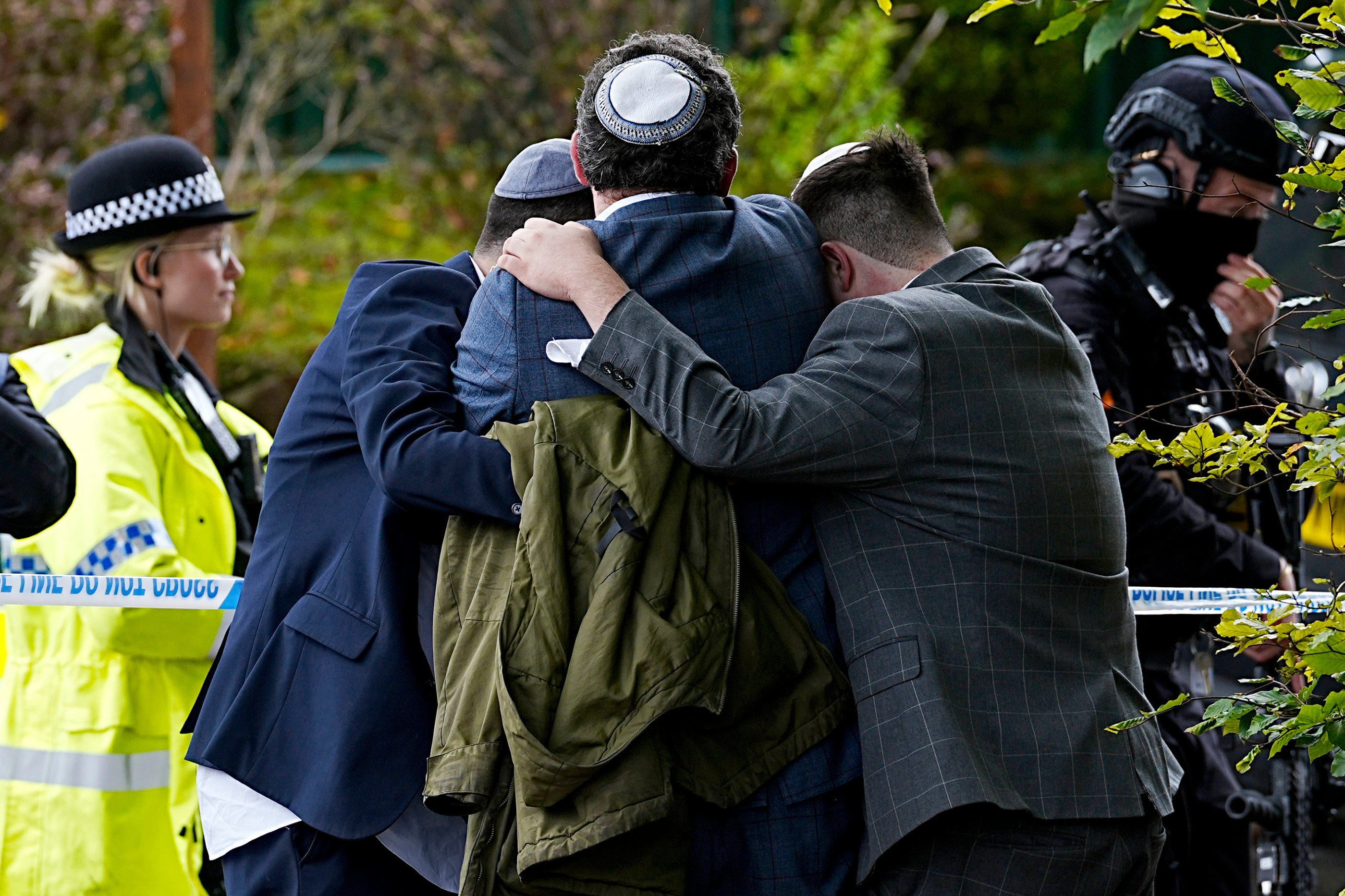 Members of the Jewish community comfort each other near to the Heaton Park Hebrew Congregation synagogue in Manchester on Thursday. Photo: PA via AP