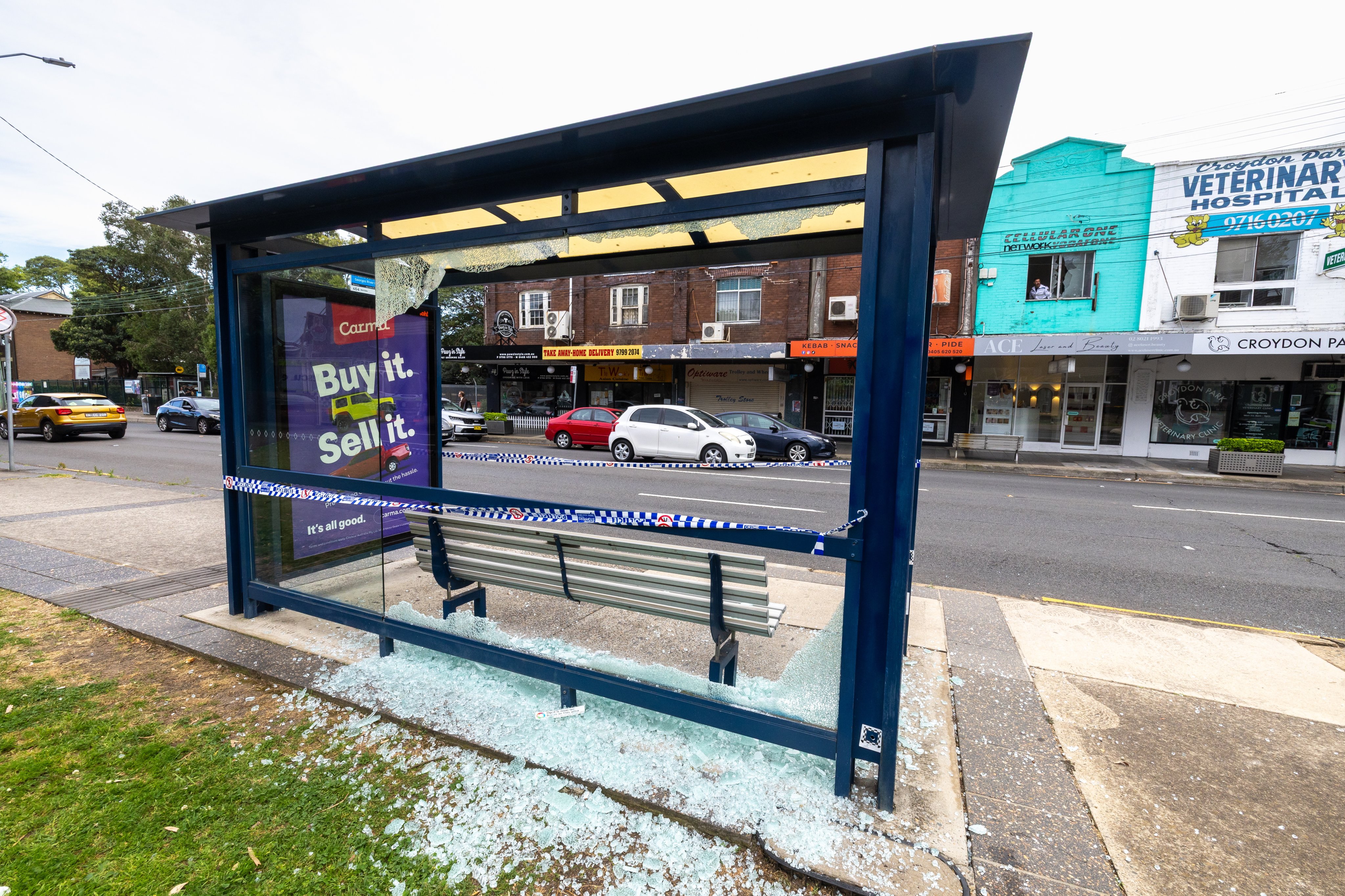 A bus stop with a shattered glass panel is seen at the scene of a shooting in Croydon Park in Sydney on Monday. Photo: EPA