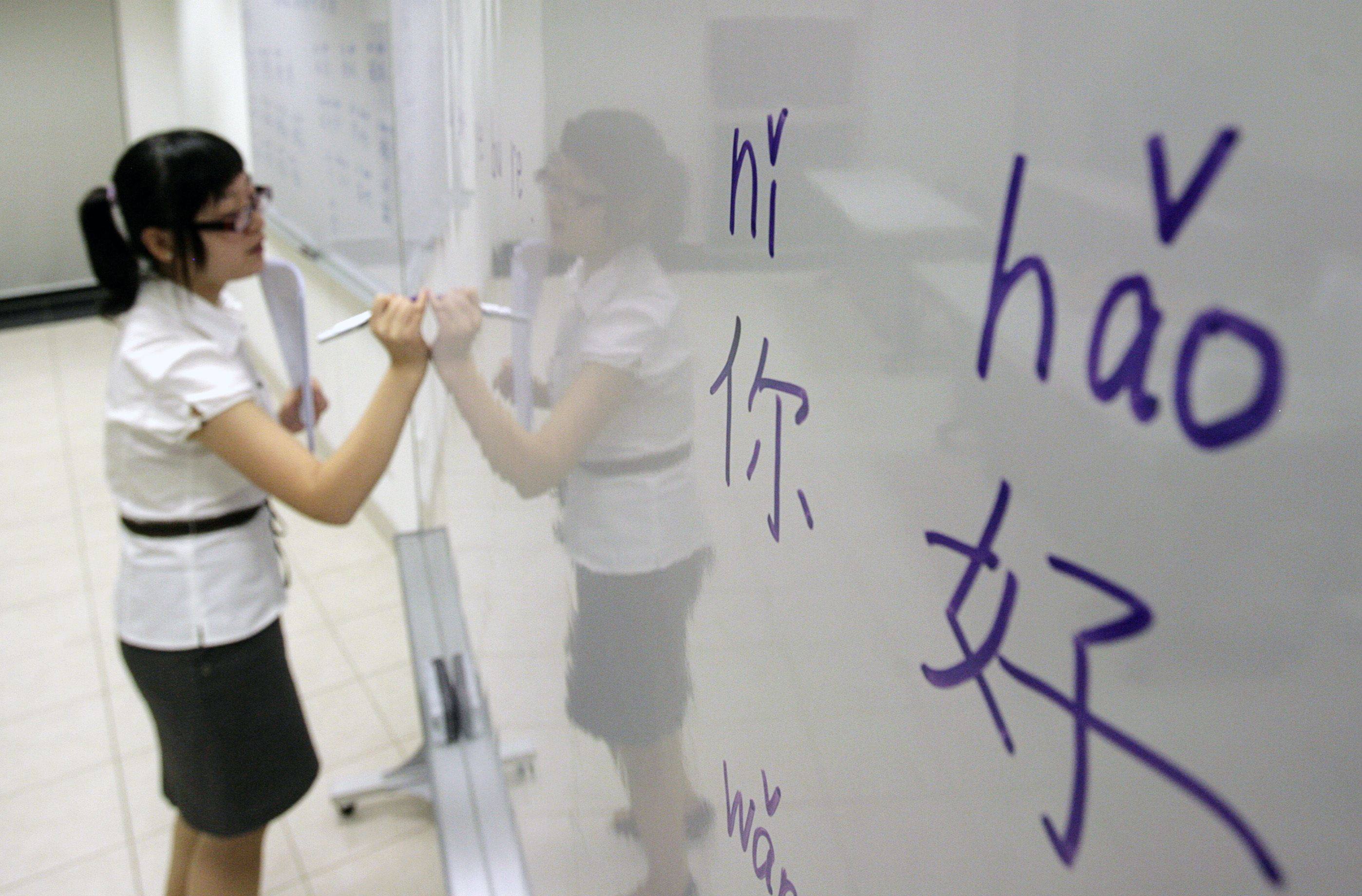 An educator writes Chinese characters on a whiteboard in Singapore. Photo: Reuters