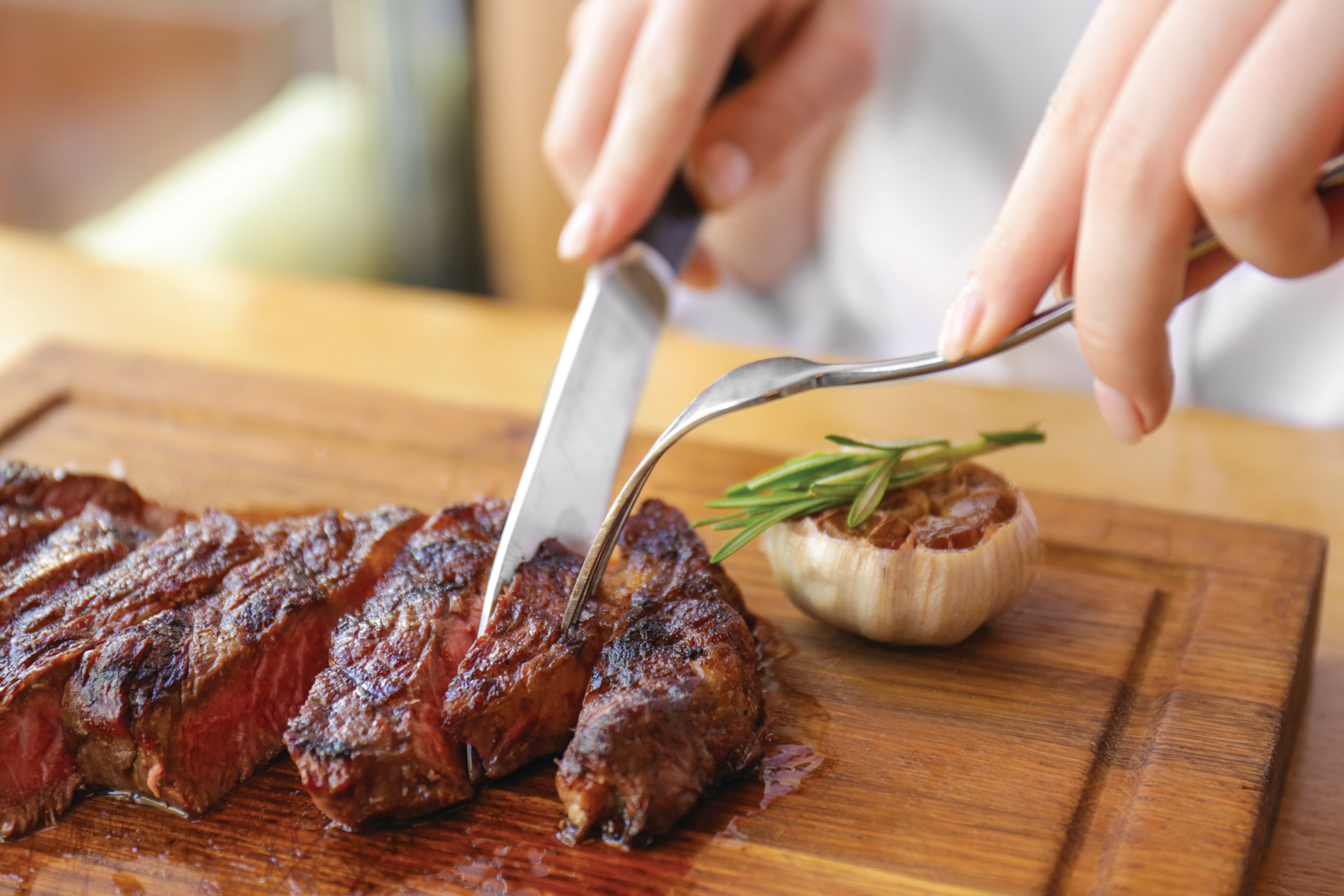 A woman cuts into a steak in a restaurant. A party in Malaysia is asking for beef to not be served during government functions. Photo: Shutterstock