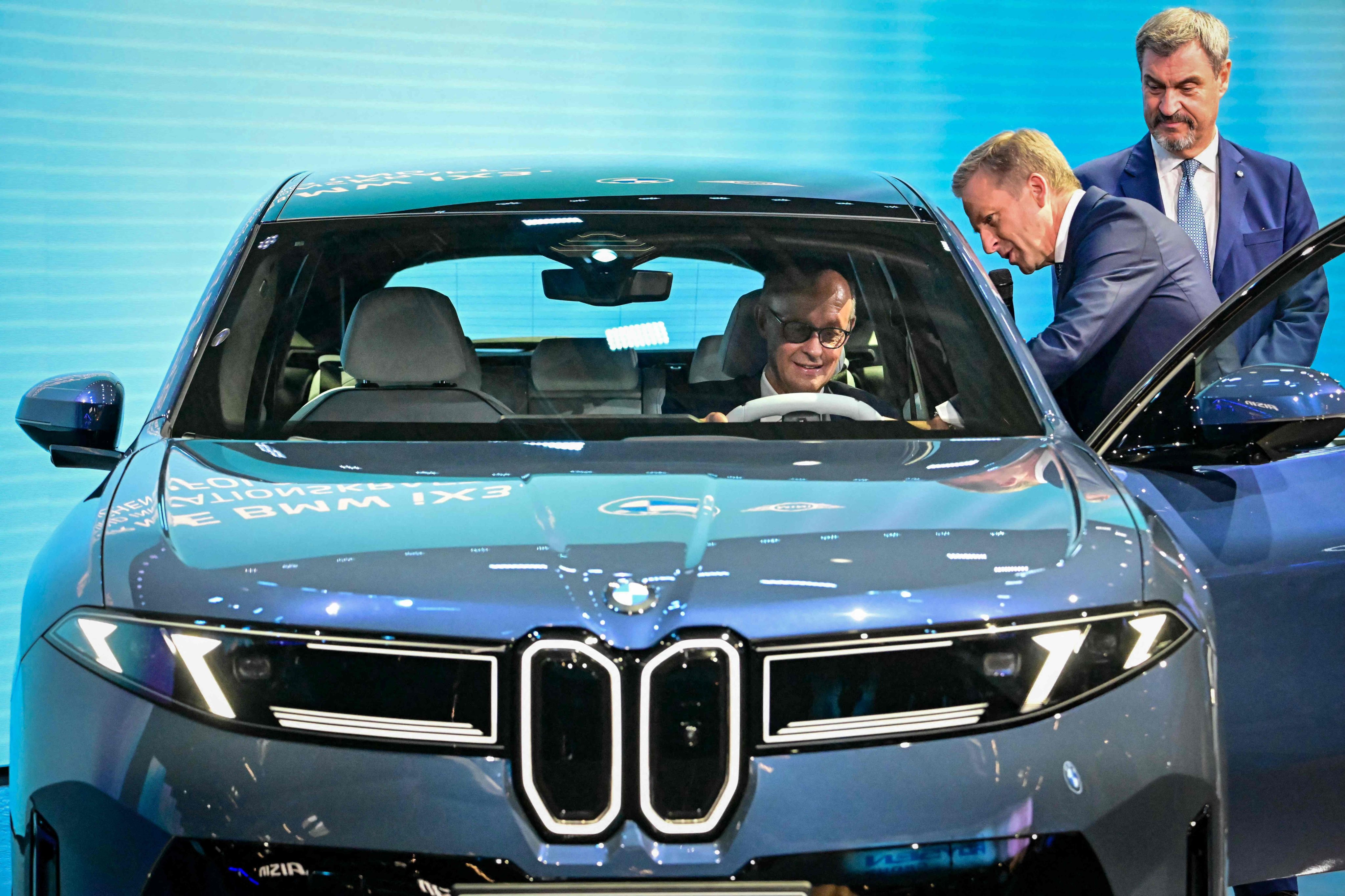 German Chancellor Friedrich Merz (left) is introduced to a BMW iX3 car by BMW CEO Oliver Zipse (centre) at a motor show in Munich. European auto manufacturers have been hit hard by EU steel tariffs. Photo: AFP