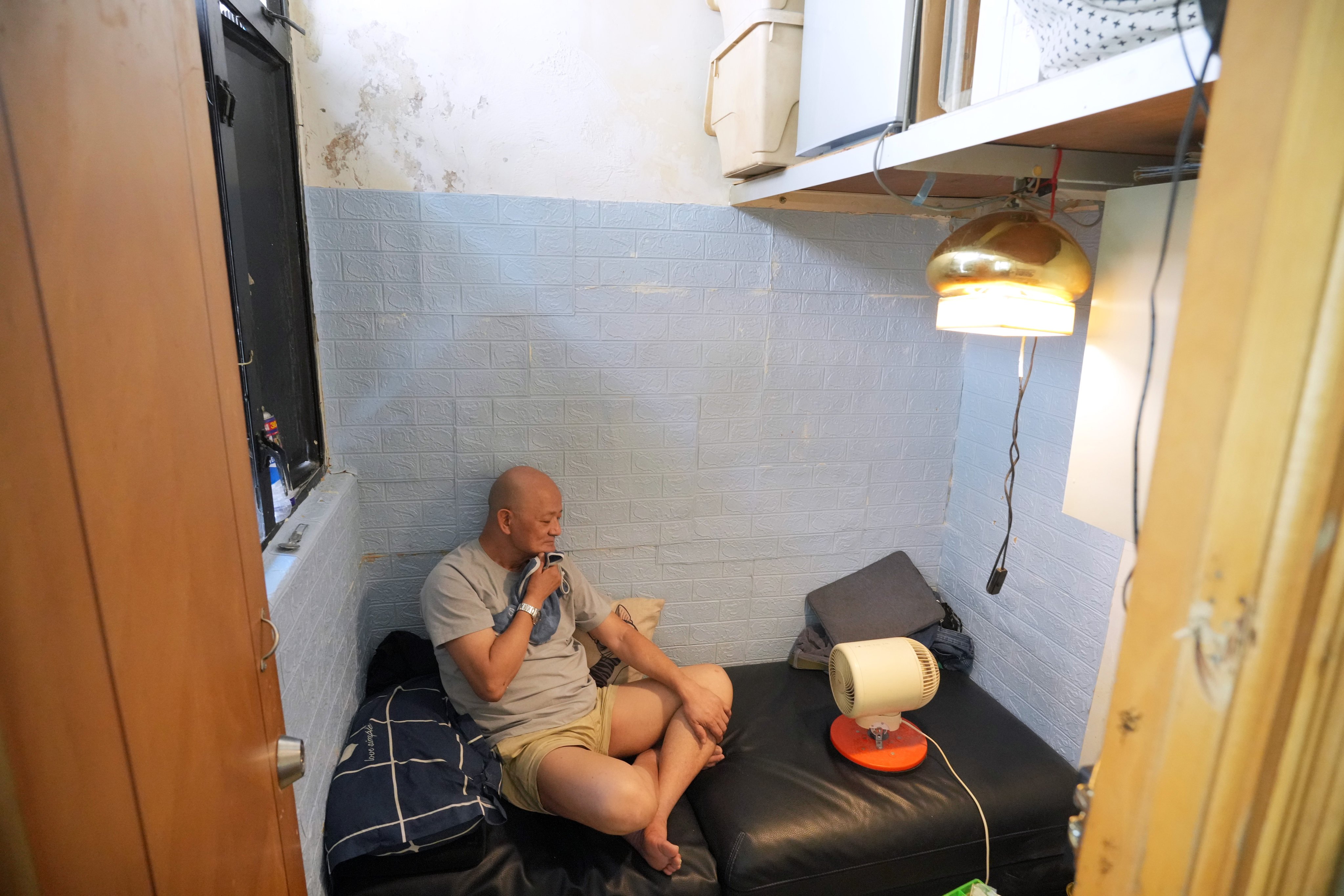 Samuel Wong, 68, uses a fan to cool himself down while resting in his subdivided flat in Sham Shui Po. Photo: May Tse