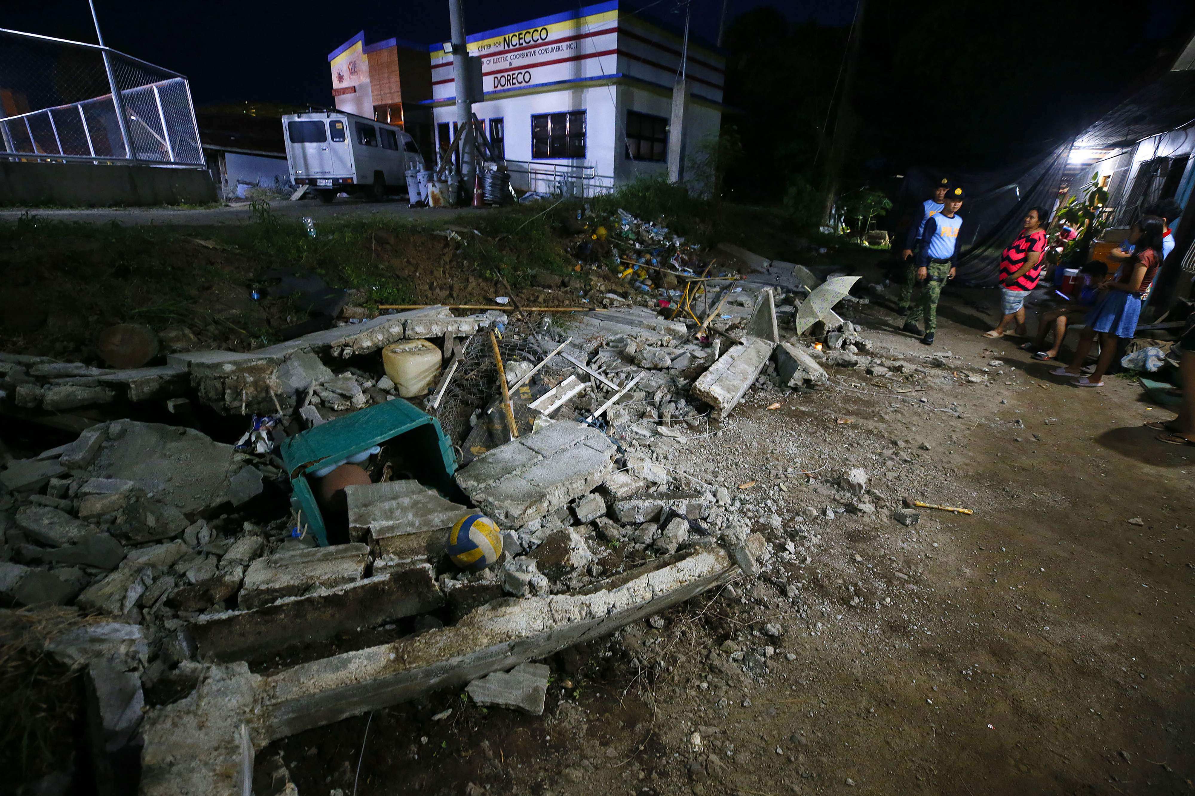 Police stand next to the rubble of a collapsed wall in the Philippines after a 7.4-magnitude earthquake. Photo: AFP