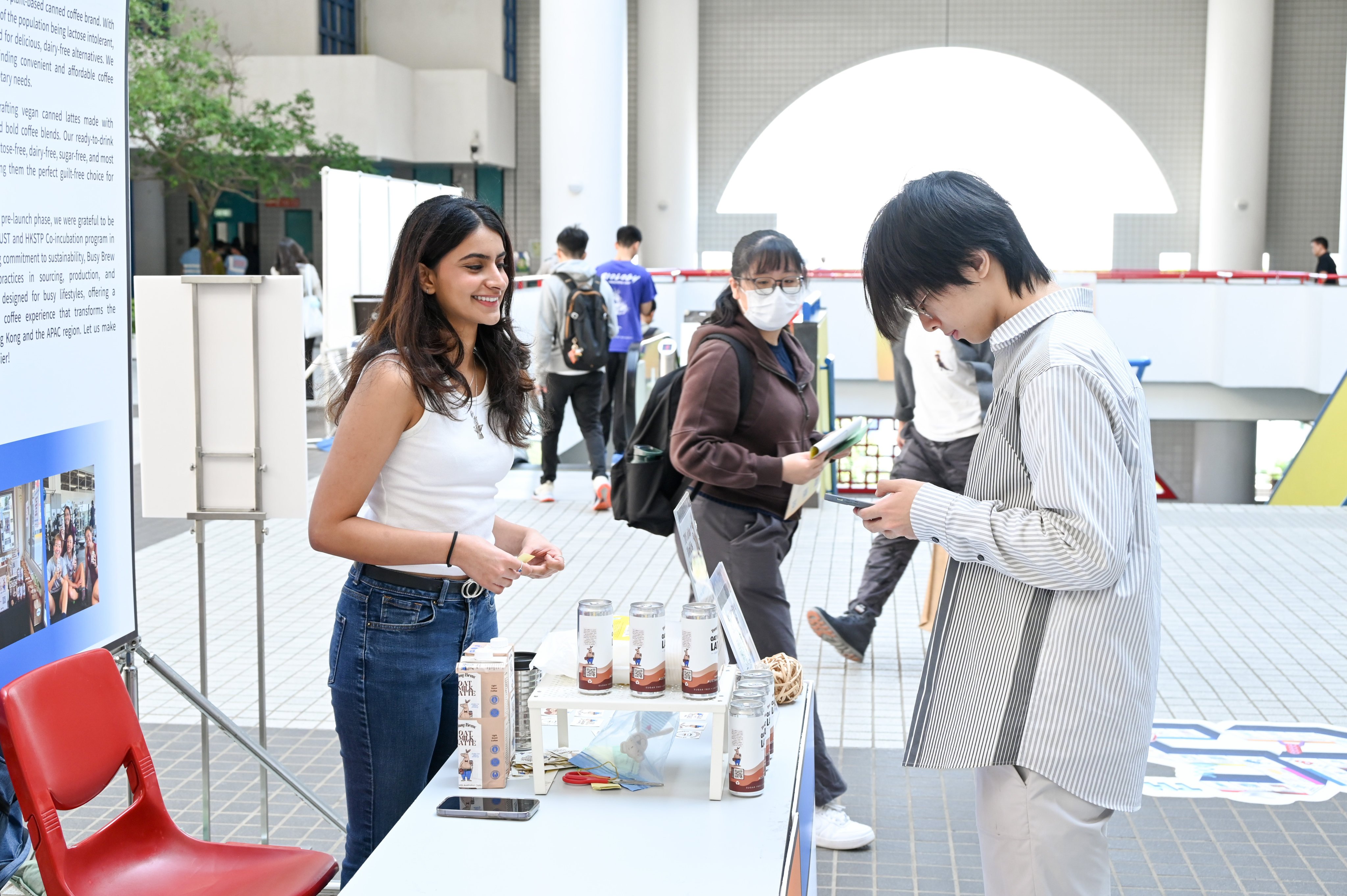 Nikita Kuwadekar (left) introduces Busy Brew’s oat milk lattes to students at a university booth. Photo: Handout