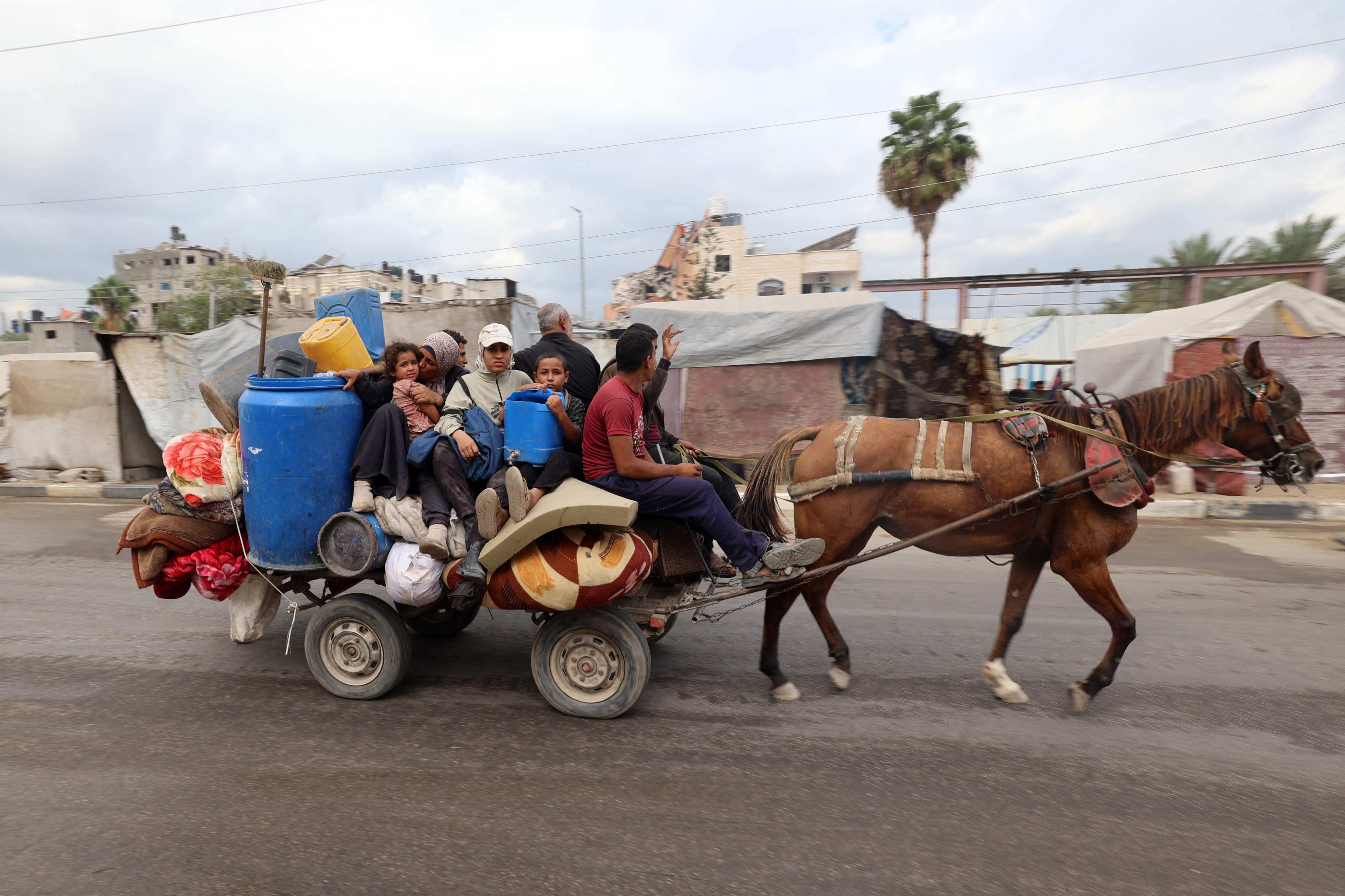 Displaced Palestinians ride a horse cart with their belongings as they pass through the Nuseirat refugee camp in central Gaza on October 12, after a ceasefire was declared. Photo: AFP