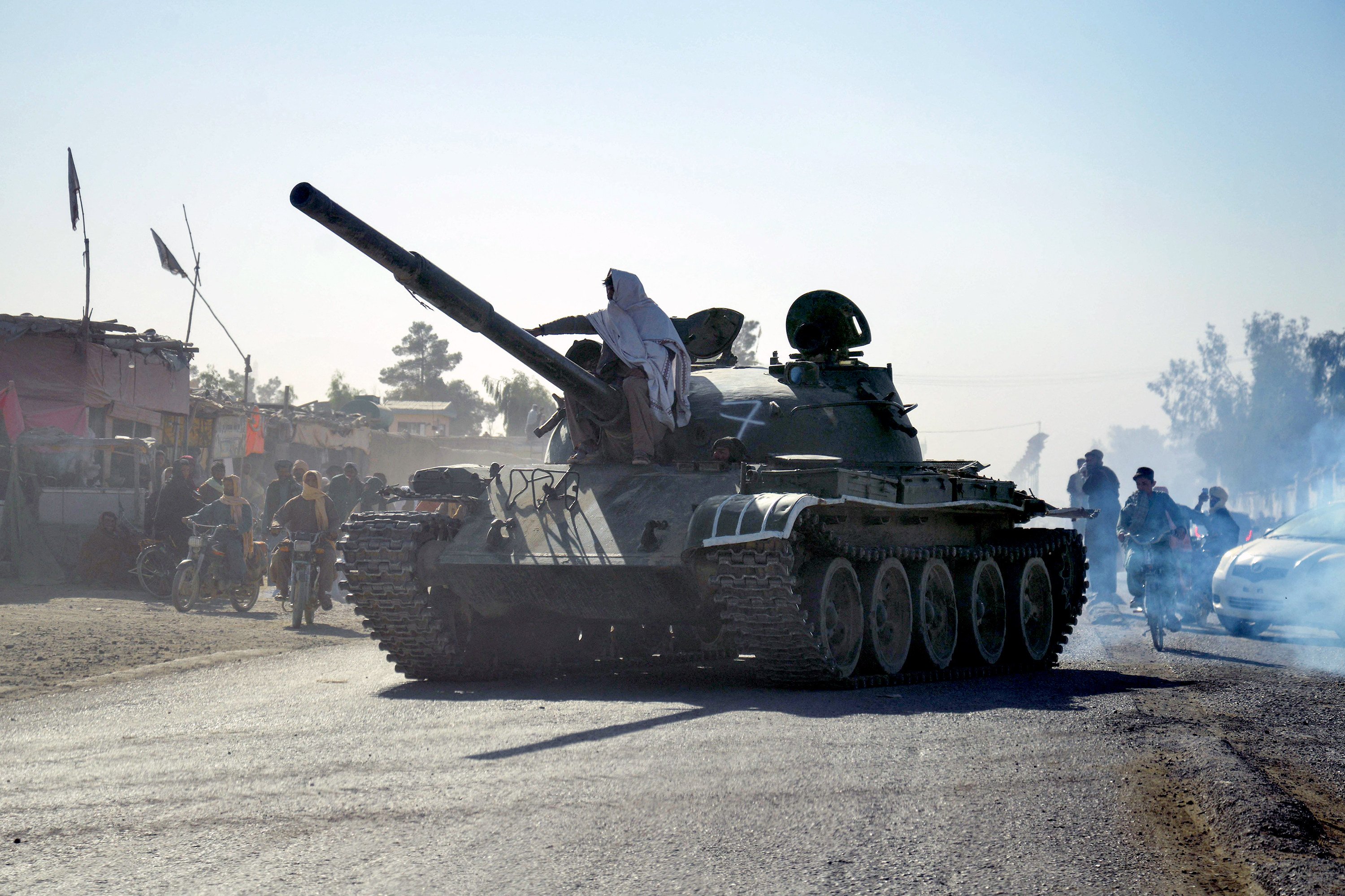 Taliban security personnel on a Soviet-era tank are followed by motorcyclists as they ride towards the border, as clashes take place between Taliban security personnel and Pakistani border forces on Wednesday. Photo: TNS