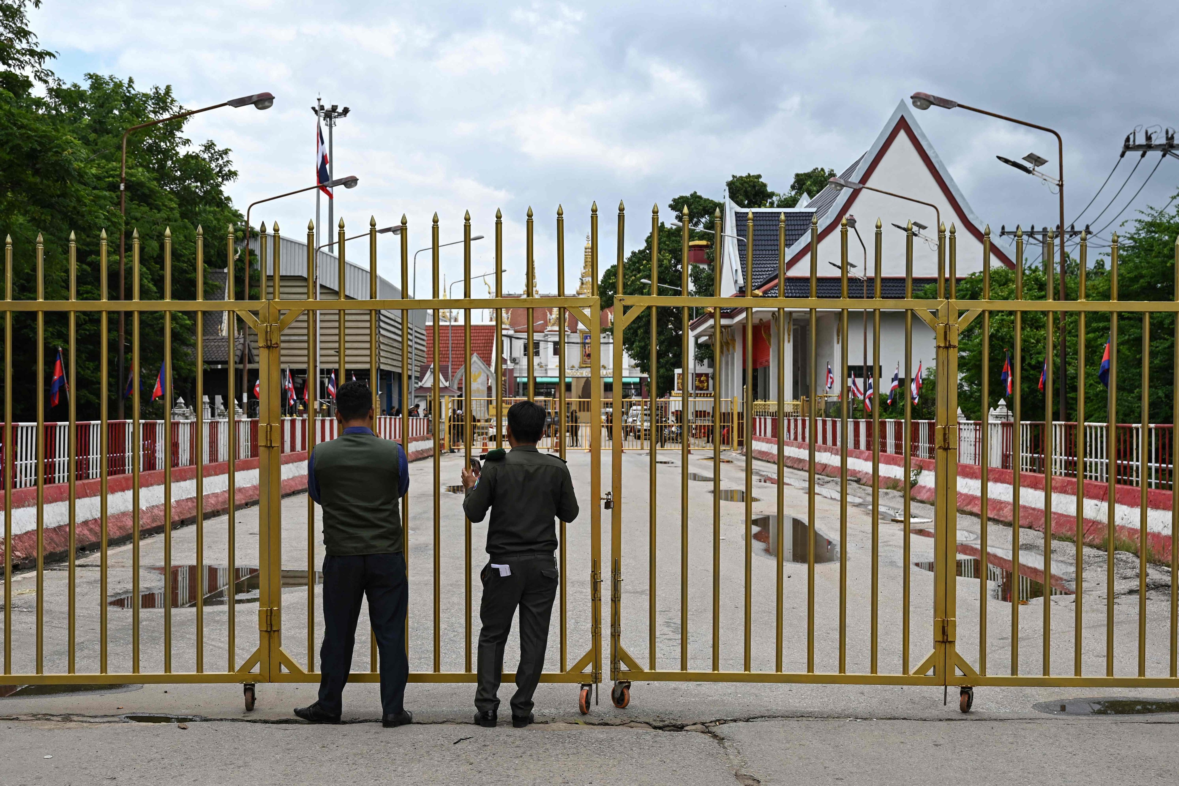 Cambodian police officials stand guard next to a closed gate at the Poipet international border checkpoint between Cambodia and Thailand. Photo: AFP