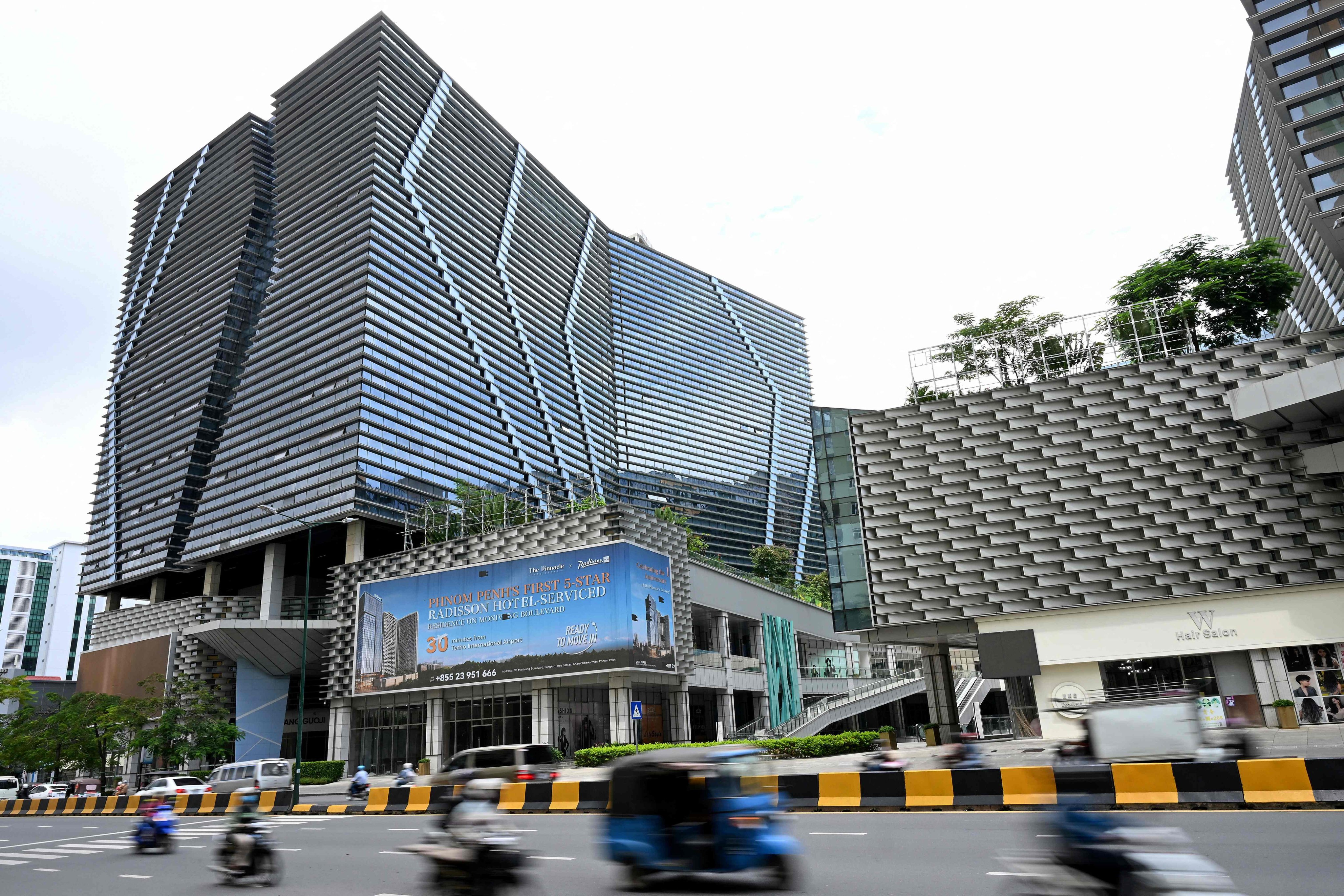 Vehicles drive past the Prince International Plaza in Phnom Penh on Wednesday. Photo: AFP