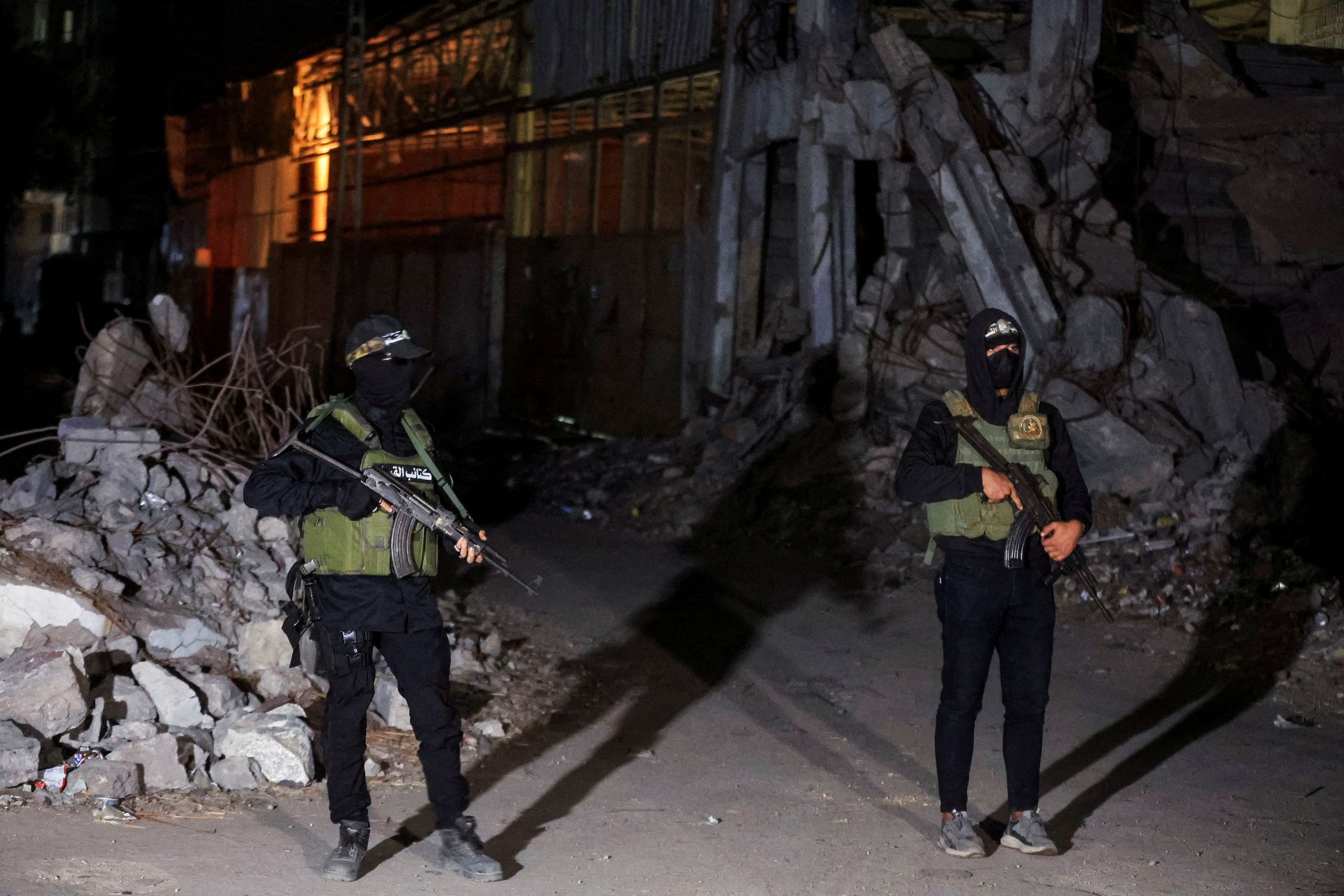 Hamas militants stand guard as Red Cross vehicles transport the bodies of hostages in Gaza City. Photo: Reuters