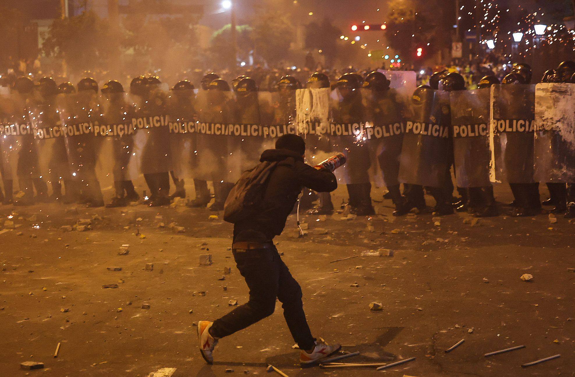 A demonstrator uses fireworks against anti-riot police in Lima on Wednesday. Photo: AFP