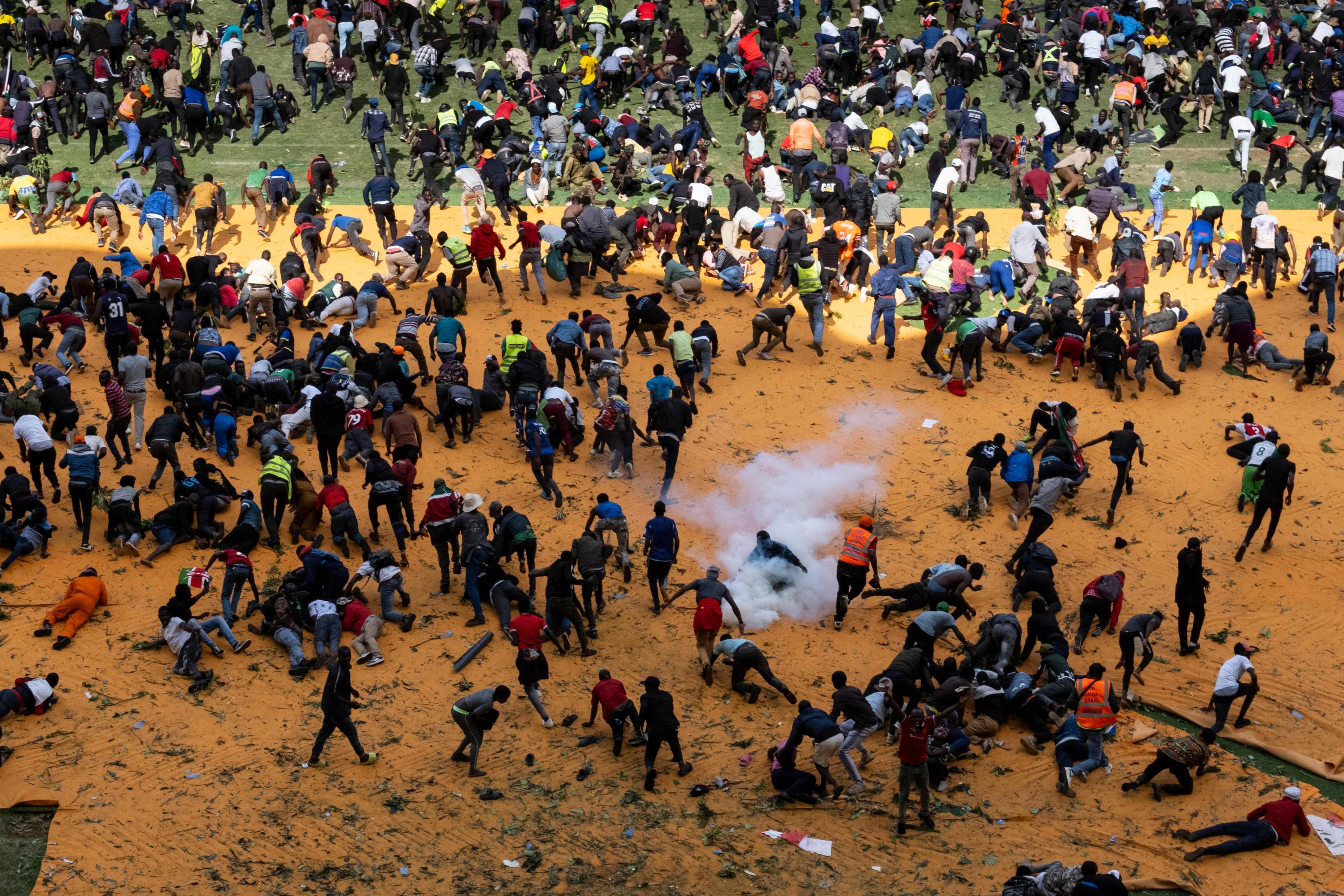 Supporters and mourners of Kenyan opposition leader Raila Odinga run for cover after gunshots and teargas were fired during a gathering for the public viewing of his coffin at the Kasarani Stadium in Nairobi on Thursday. Photo: AFP