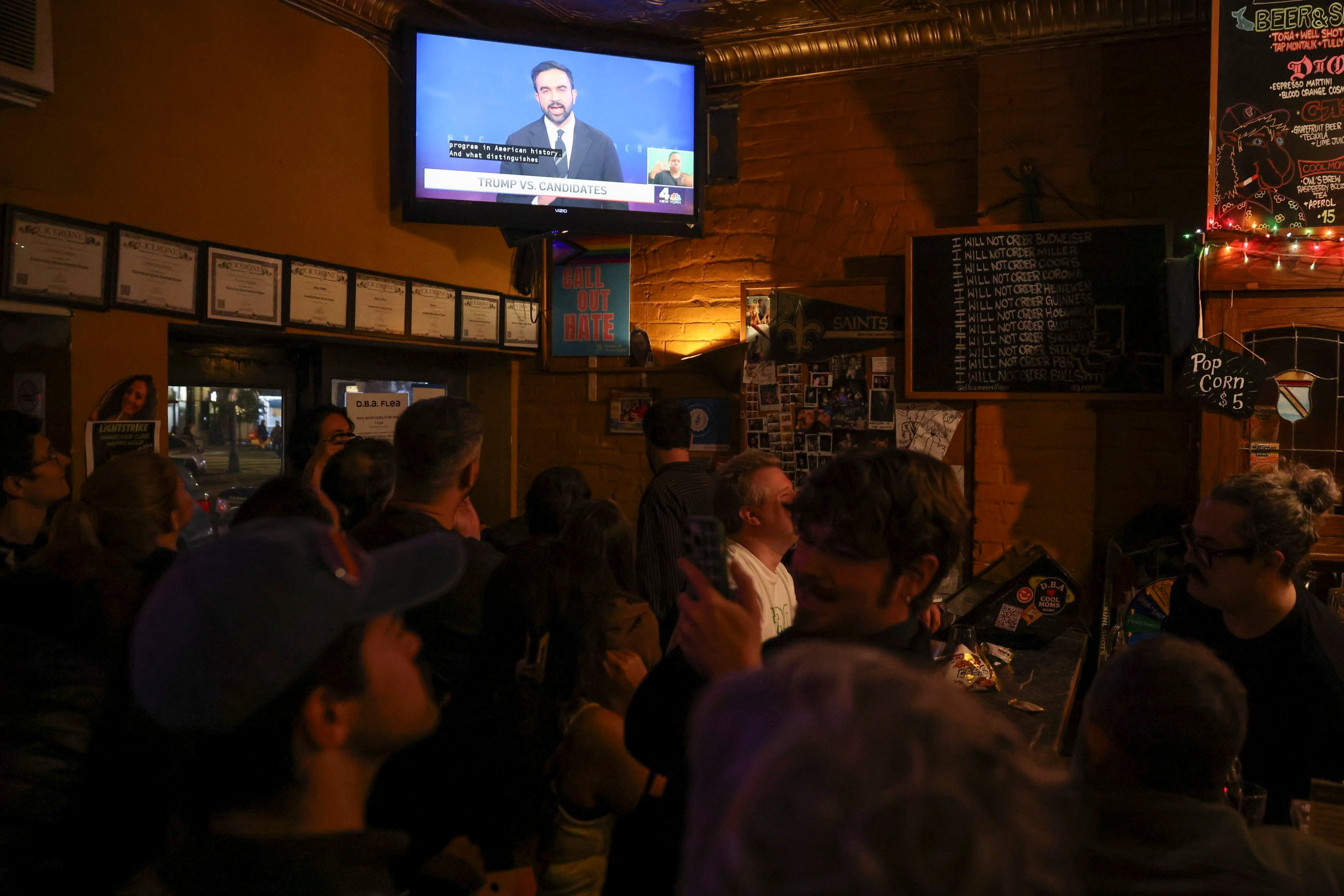 People watch Democratic nominee Zohran Mamdani speak on a screen at a local bar in New York. Photo: EPA