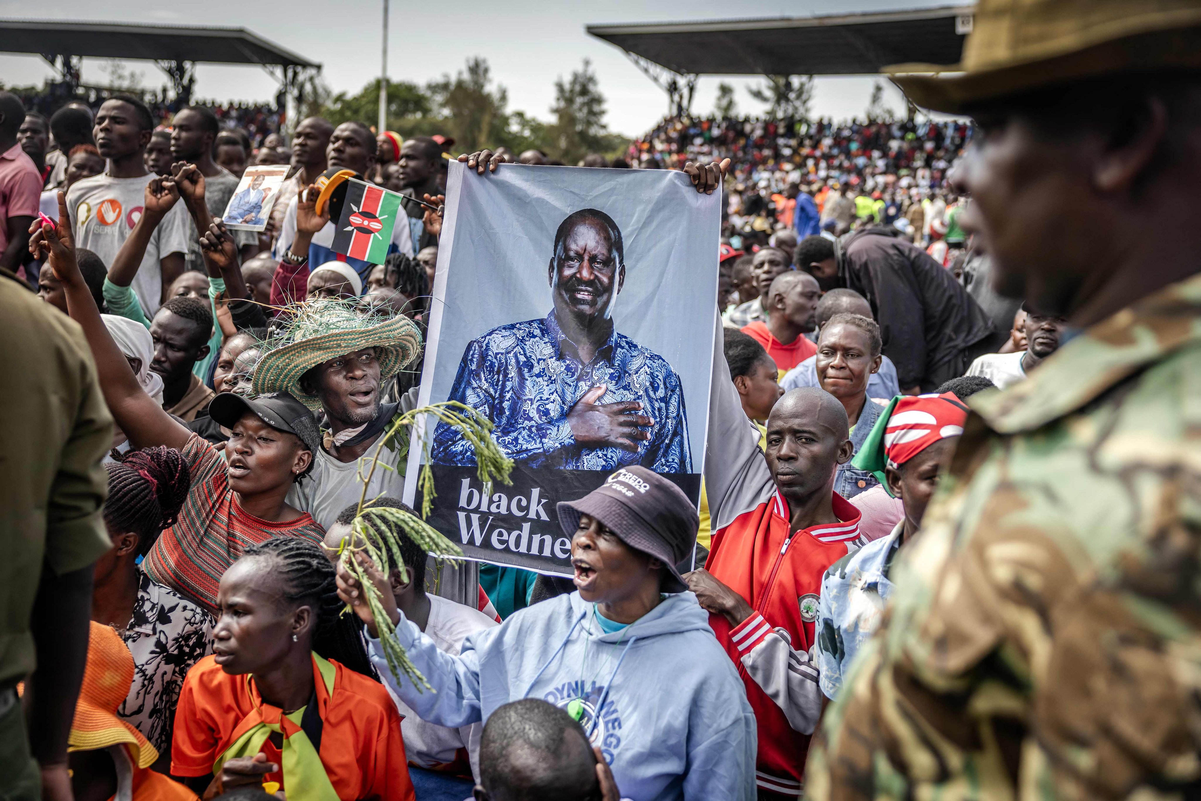 Supporters of Kenyas opposition leader Raila Odinga hold a banner as mourners line up to view his coffin upon the arrival of his funeral proceedings in Kisumu, Kenya, on Saturday. Photo: AFP