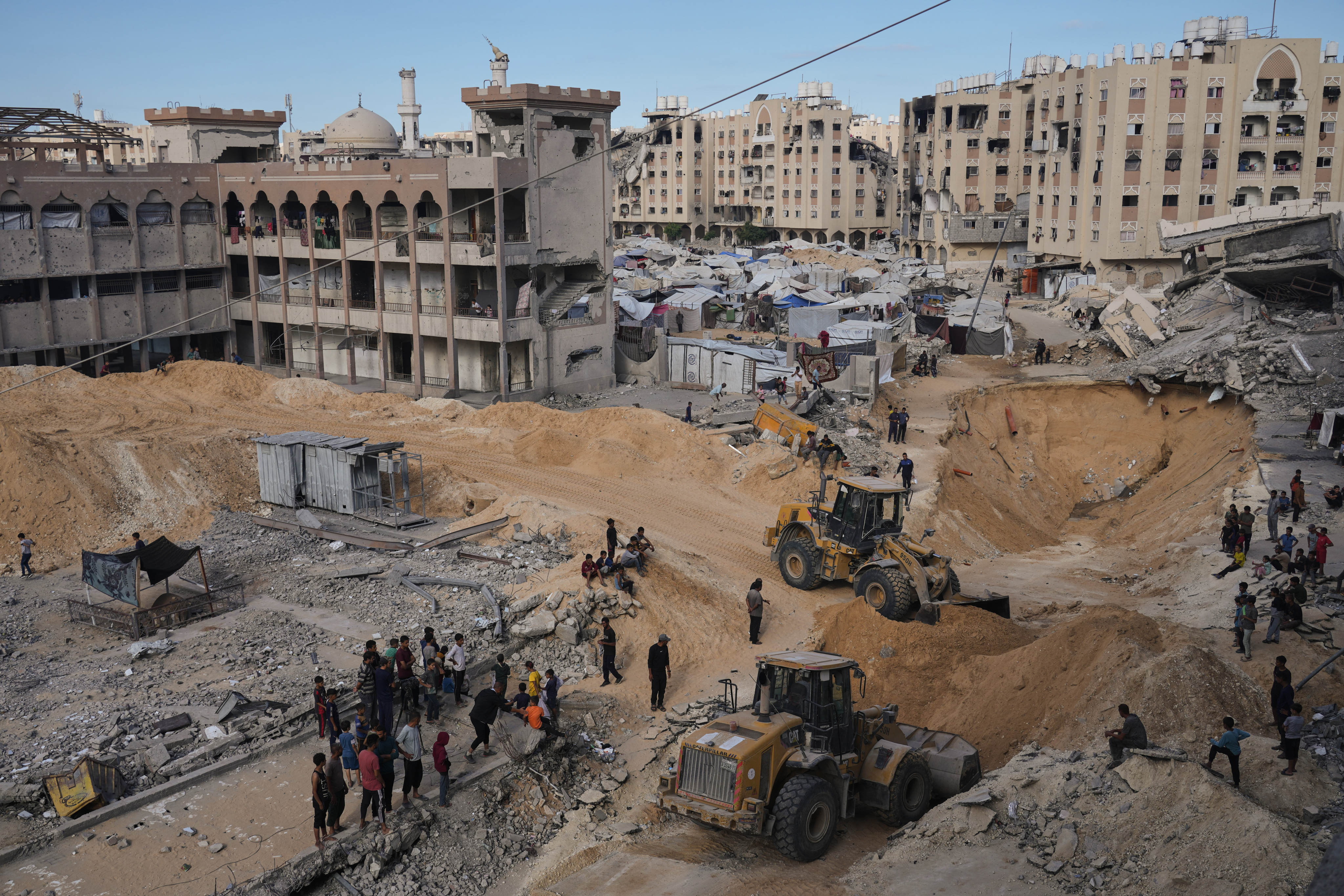 Palestinians watch members of the Hamas militant group search for bodies of the hostages in an area in Hamad City, Khan Younis, in the southern Gaza Strip on Saturday. Photo: AP