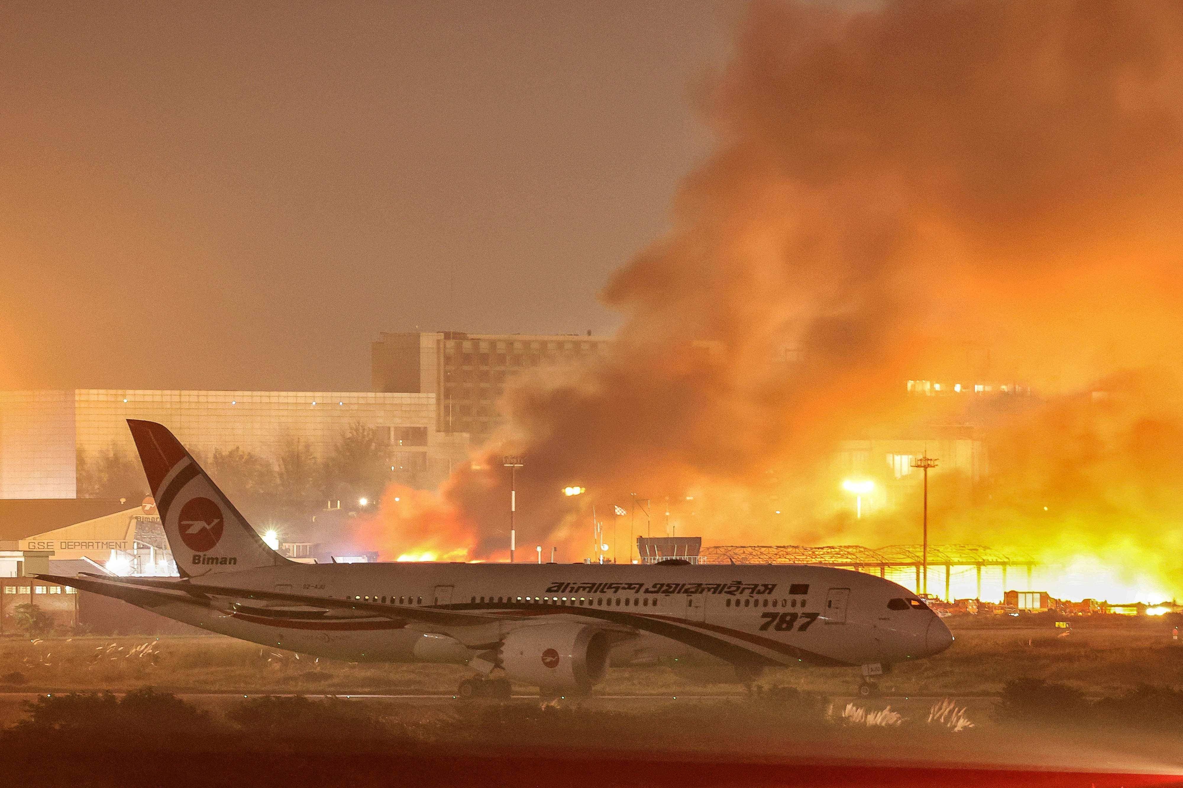 An airline plane stands on the tarmac as firefighters try to extinguish a fire that broke out in the cargo section of Hazrat Shahjalal International Airport in Dhaka on Saturday. Photo: AFP