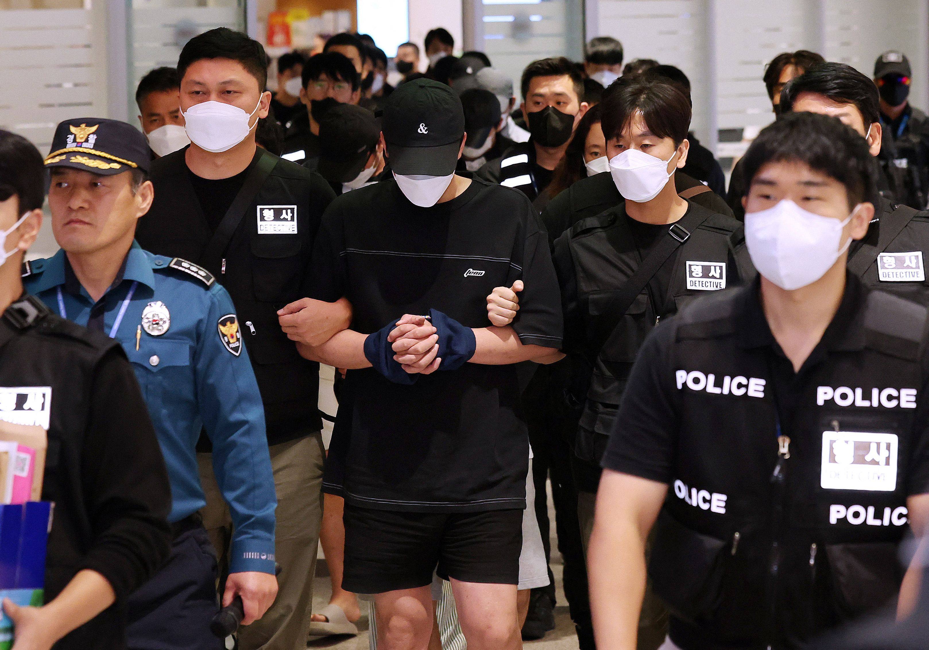 Police officers escort repatriated South Koreans who were detained by authorities in Cambodia over alleged cyberscam operations upon their arrival at Incheon International Airport on Saturday. Photo: Yonhap/AFP