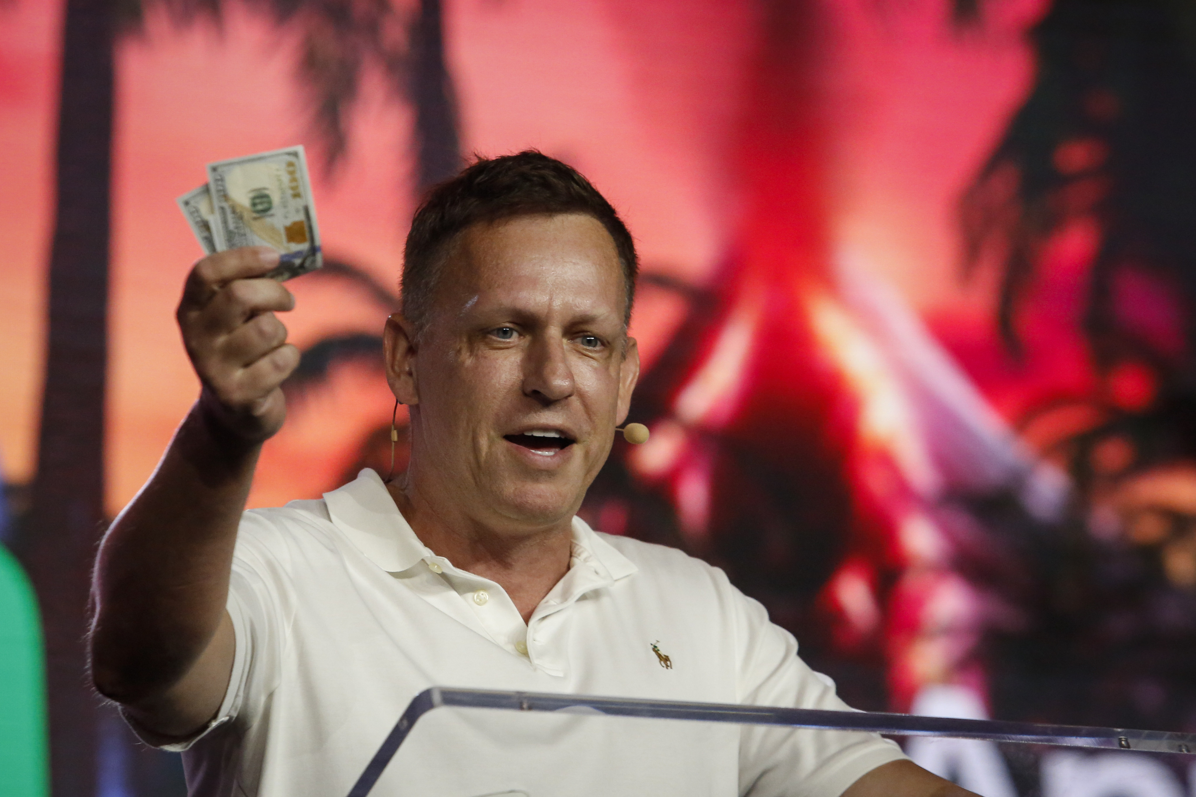 Peter Thiel, co-founder of PayPal, Palantir Technologies, and Founders Fund, holds hundred dollar bills as he speaks during the Bitcoin 2022 Conference at Miami Beach Convention Center on April 7, 2022 in Miami, Florida. Photo: Getty Images