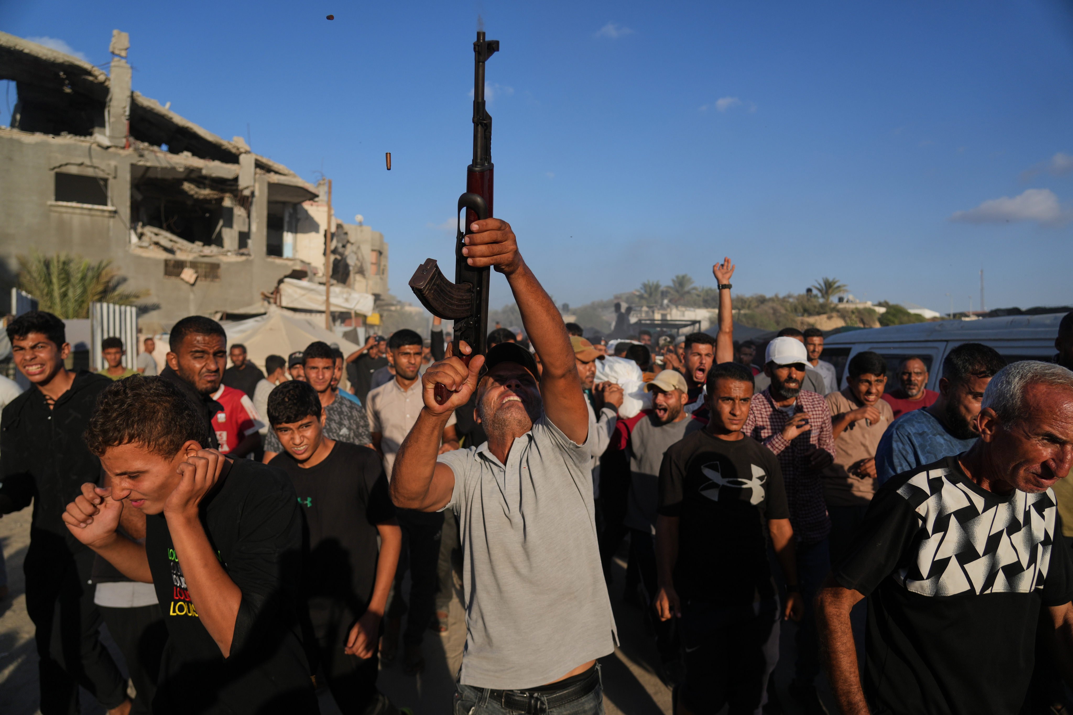 An armed man shoots in the air during the funeral of Palestinians killed by Israeli fire, in Deir al-Balah, Gaza Strip. Photo: AP