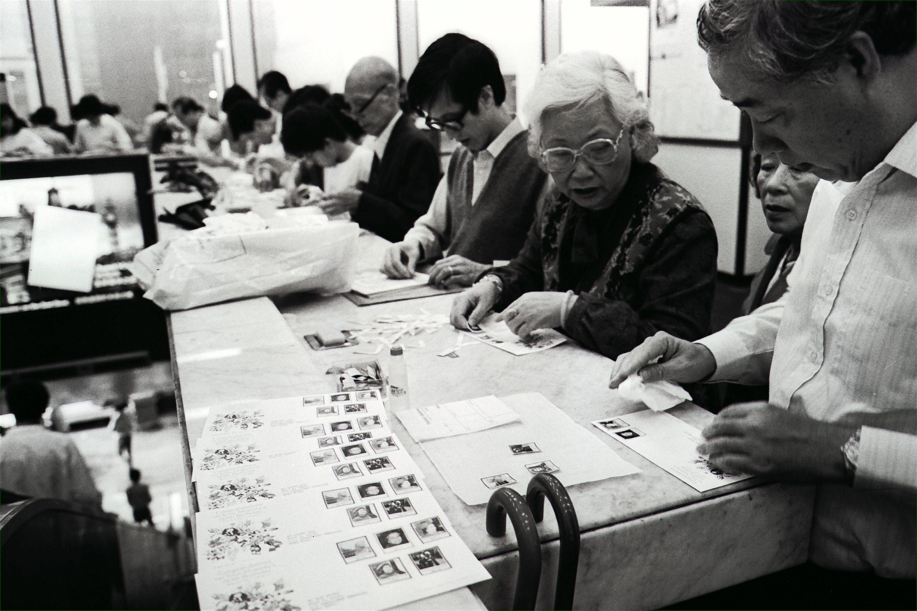 Eager philatelists in Hong Kong carefully stick a set of stamps onto first-day covers inside a post office in 1986. The stamps were issued to commemorate the Queen’s 60th birthday. Photo: SCMP Archives