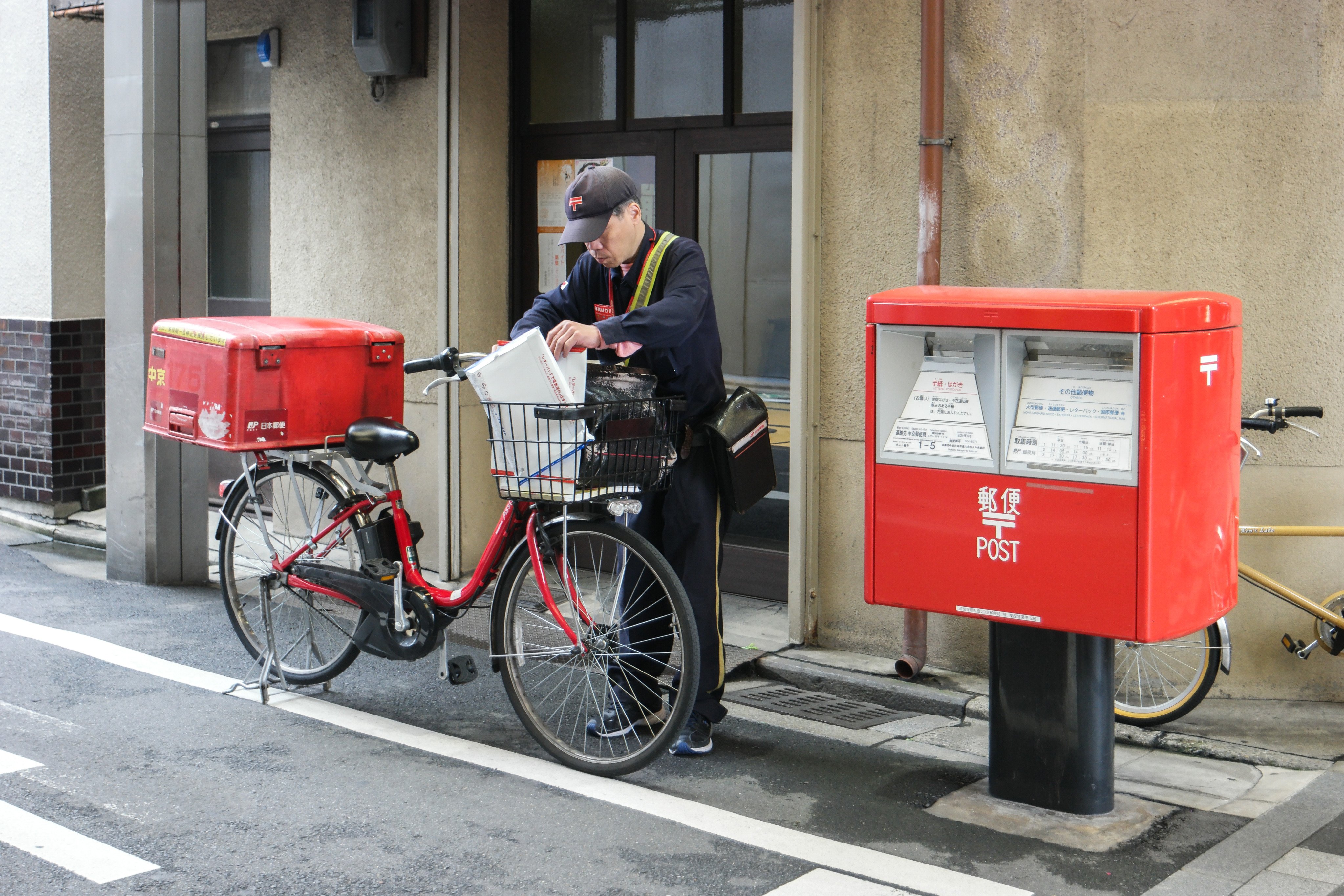 A postman sorts mail near a postbox in Japan. Photo: Shutterstock