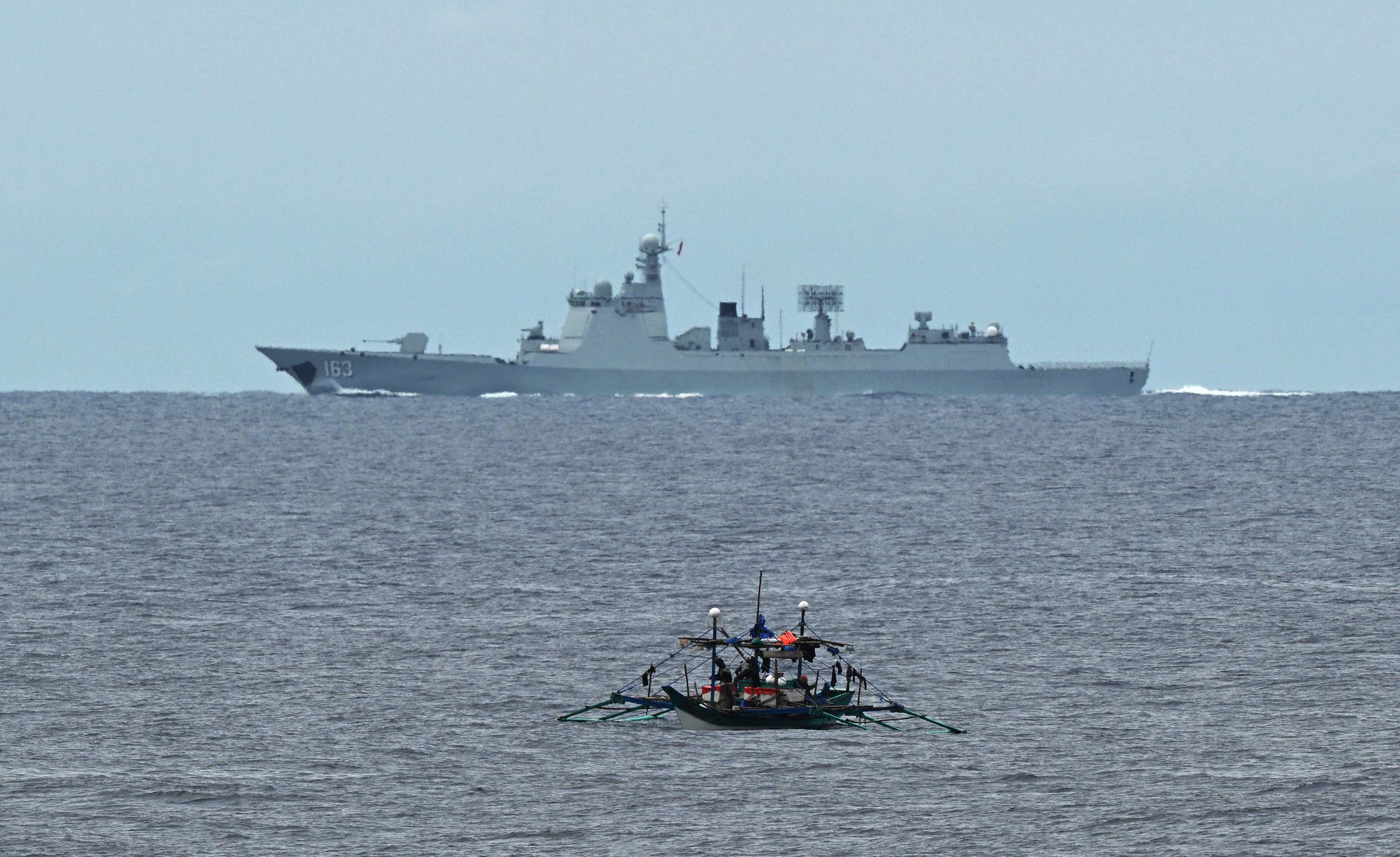 A Chinese navy ship speeds past a Philippine fishing boat in the disputed South China Sea last month. Photo: AFP
