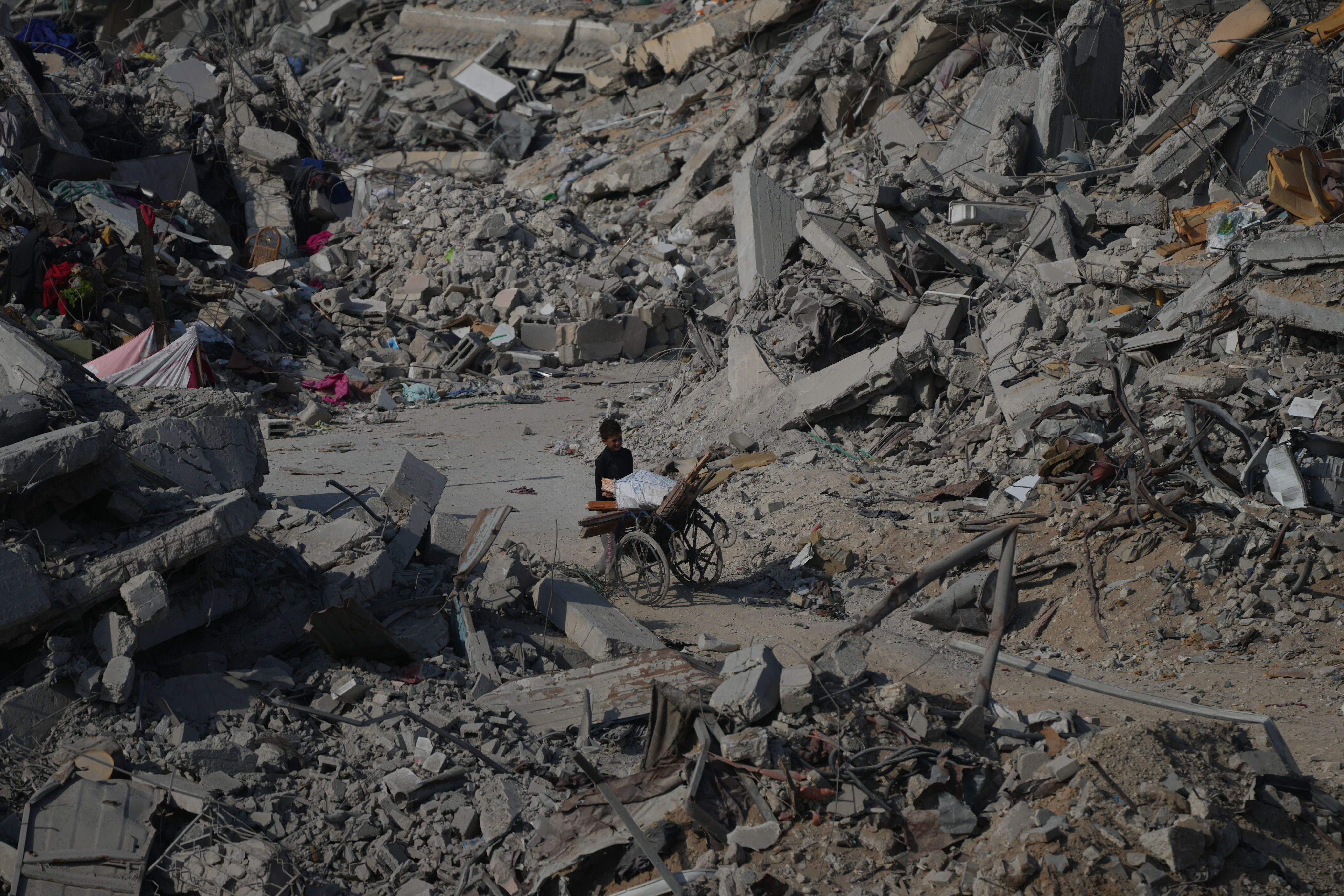 A boy pushes a wheelbarrow through the rubble of buildings destroyed in the war between Israel and Hamas, in the al-Nafaq area of the Sheikh Radwan neighbourhood in Gaza City on Friday. Photo: AP