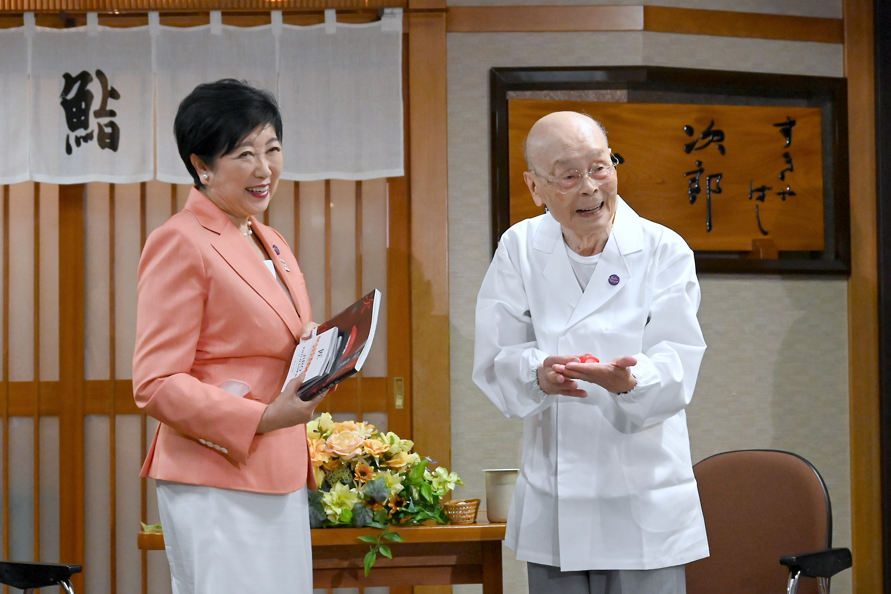 Jiro Ono (right) shows a gift from Tokyo Governor Yuriko Koike to celebrate his 100th birthday in front of  Sukiyabashi Jiro on September 18. Photo: Bureau of Social Welfare, Tokyo Metropolitan Government/AP