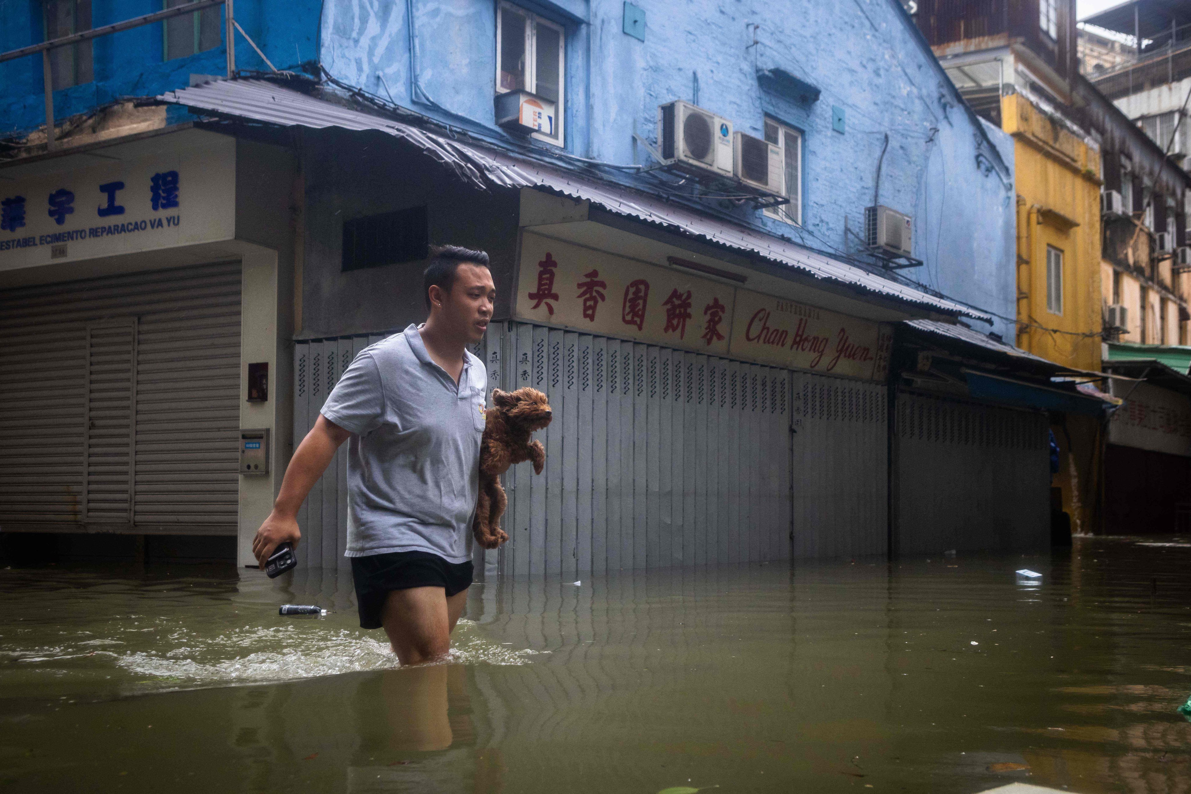 A man holds his dog while walking through a flooded street during the passage of Super Typhoon Ragasa in Macau on September 24. Photo: AFP